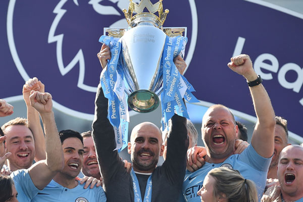 Manajer Spanyol Manchester City Pep Guardiola mengangkat trofi Liga Premier karena dia dikelilingi oleh stafnya 