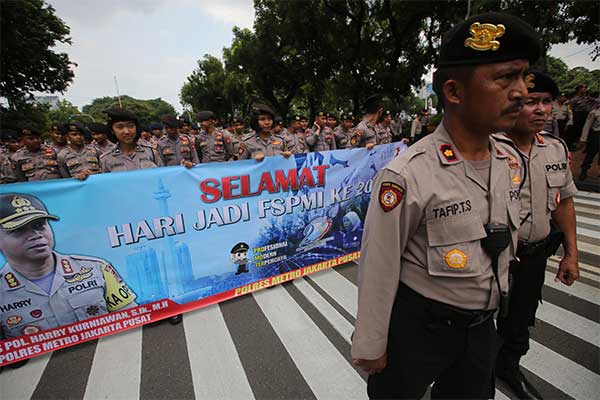 Ilustrasi -- Petugas gabunga Polisi dan TNI membentangkan sepanduk ucapan hari jadi FSPMI saat berjaga dalam aksi long march buruh menuju Is