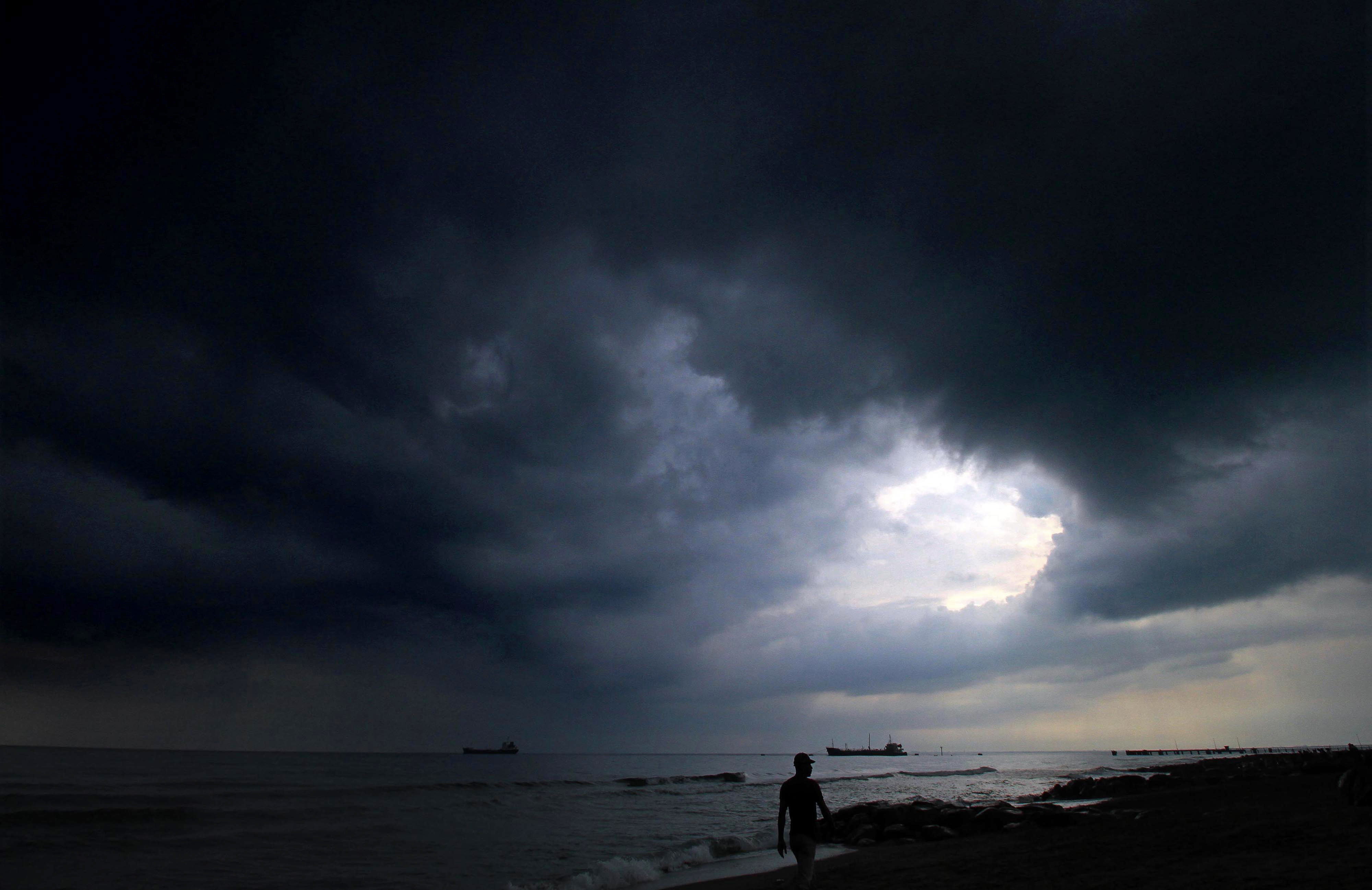 Nelayan melintas di bawah awan hitam yang menyelimuti langit.