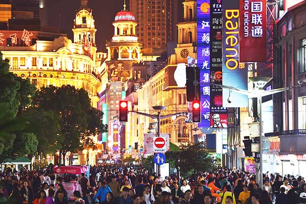 Orang-orang berjalan melalui area perbelanjaan di Shanghai, Tiongkok, kemarin.