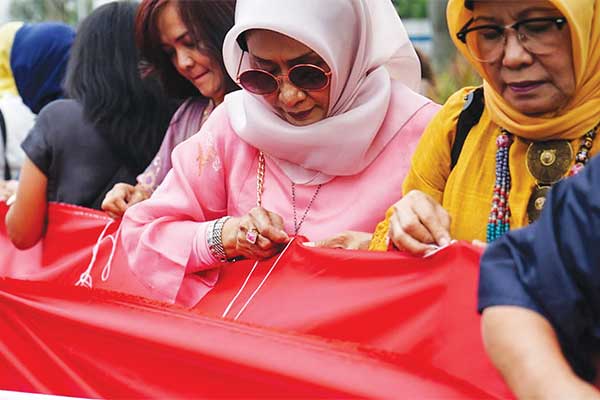Masyarakat dari Komunitas Indonesia Maju menjahit kain berwarna merah dan putih pada acara Refl eksi 111 Tahun Kebangkitan Nasional di Gedun