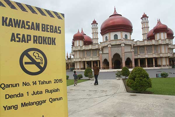 Warga melintas di depan banner kawasan bebas asap rokok di Halaman Masjid Agung Baitul Makmur Meulaboh, Aceh Barat, Aceh, Kamis (4/1).