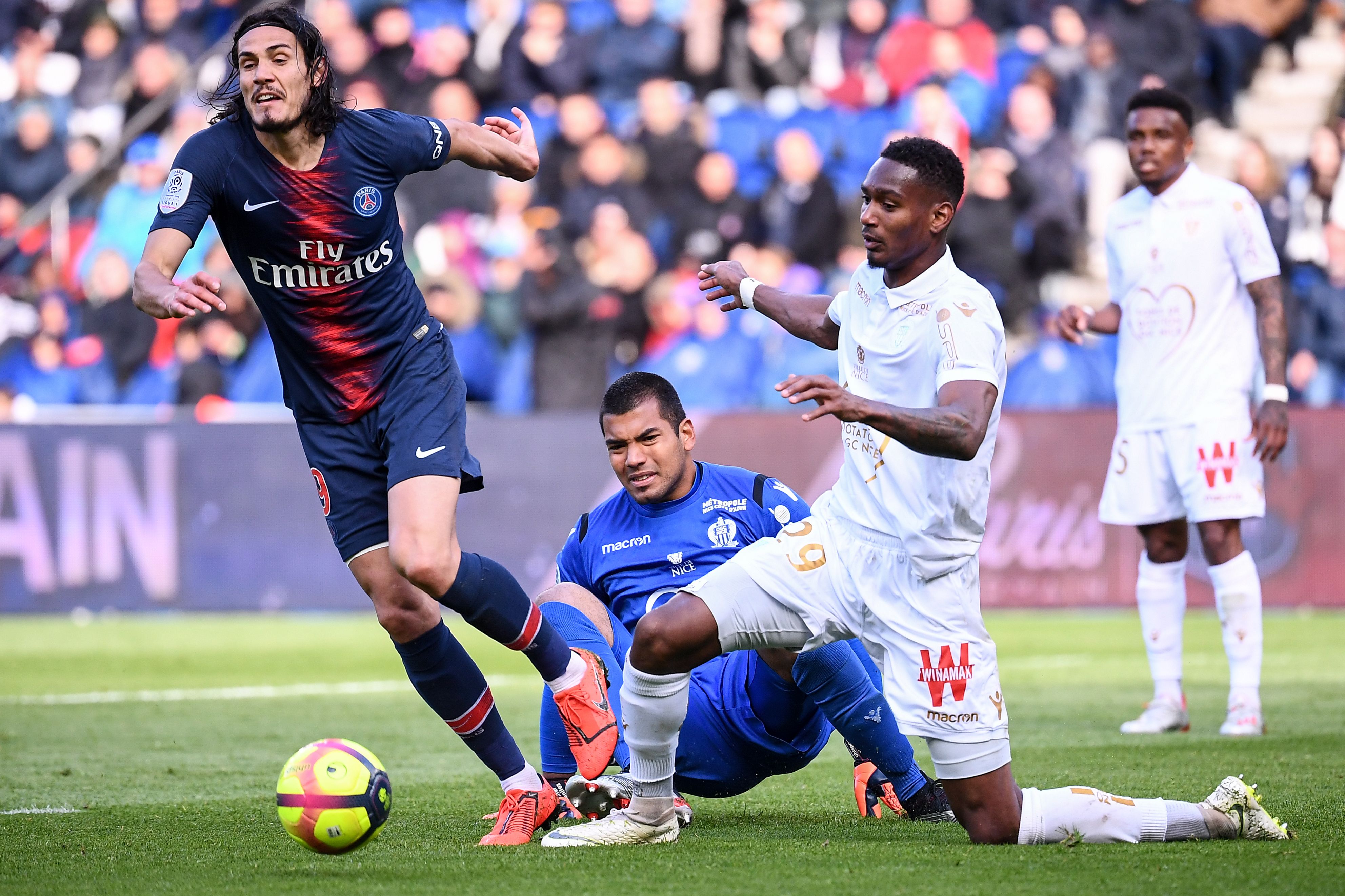 Penyerang PSG Edinson Cavani melewati penjaga gawang dan pemain belakang Nice.