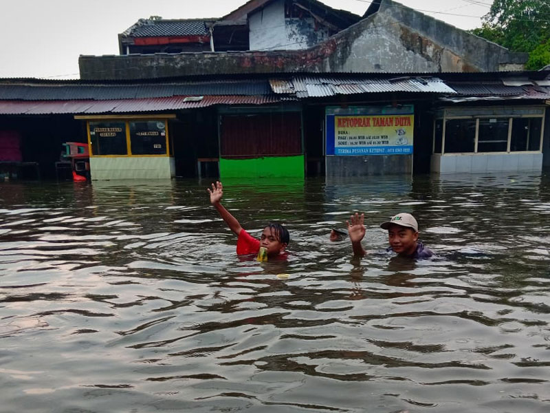 Dua orang anak bermain di genangan banjir di Jalan Taman Duta- Simpang Raya Bogor, Kelurahan Cisalak, Sukmajaya, Kota Depok