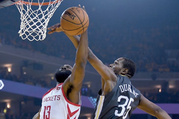James Harden (kiri), bintang tim Houston Rockets, berupaya memasukkan bola, tapi Kevin Durant dari Golden State Warriors memblok nya