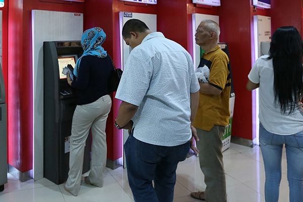 Nasabah sedang bertransaksi di mesin ATM