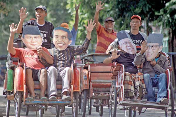 Warga menaiki becak sambil menggunakan penutup wajah bergambar pasangan capres-cawapres peserta Pemilu 2019, Joko Widodo-Ma’ruf Amin dan Pra