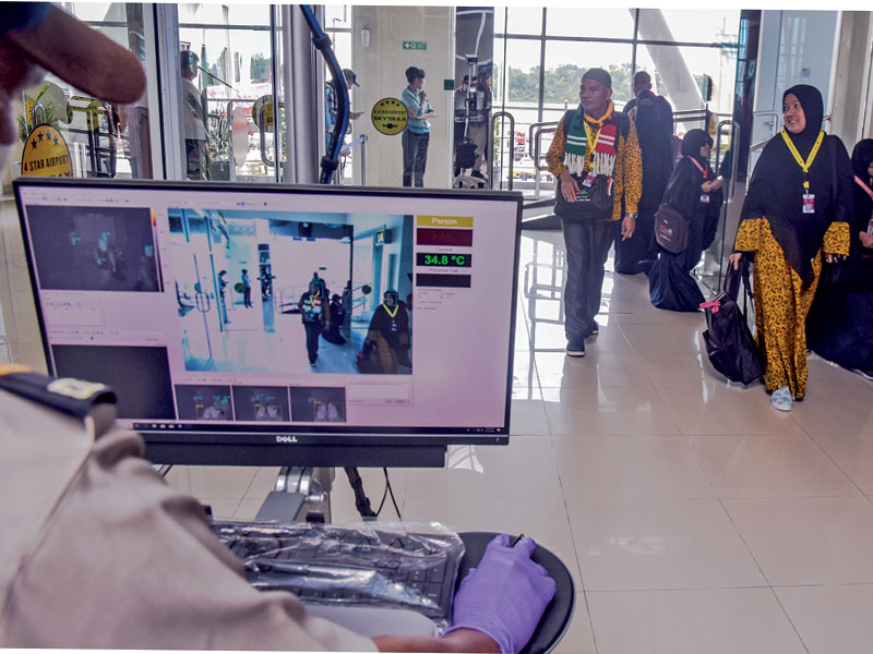 Penumpang berjalan melewati pemindai panas tubuh di terminal kedatangan internasional Bandara Sultan Syarif Kasim II, Kota Pekanbaru, Riau,