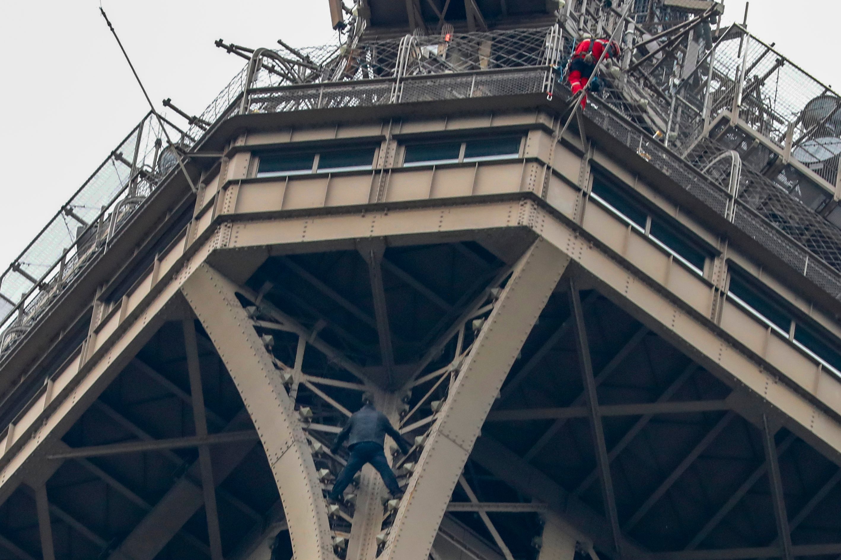 Petugas pemadam kebakaran berusaha mencapai seorang pria yang memanjat Menara Eiffel.