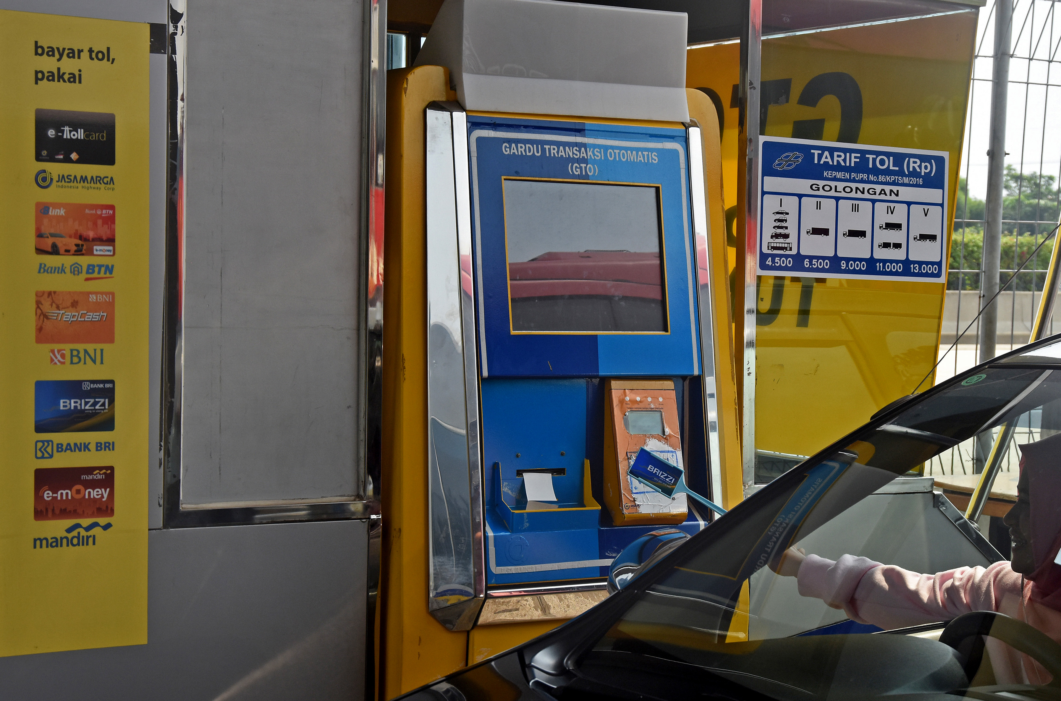 Pengendara melakukan transaksi non tunai menggunakan kartu e-Toll.