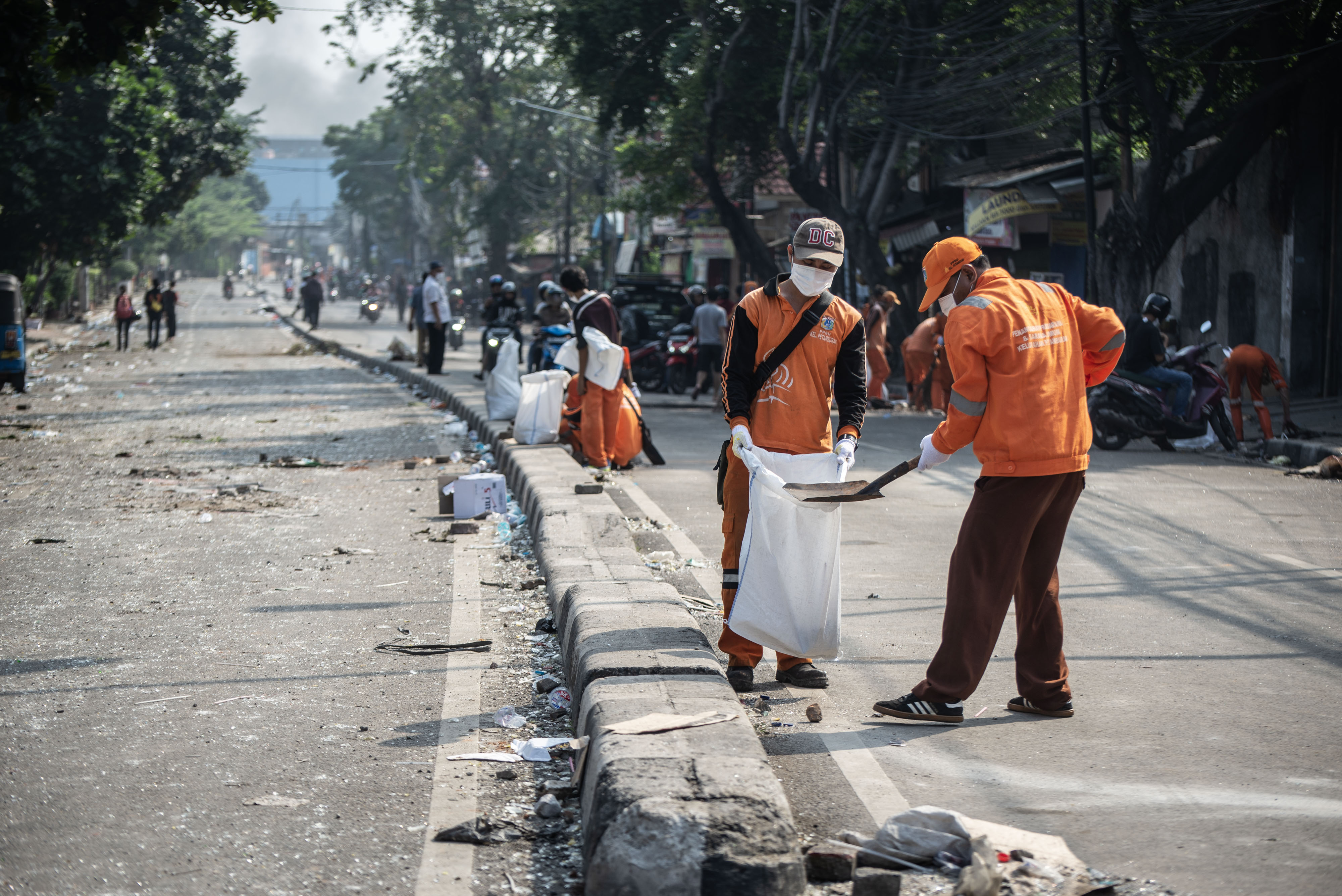 Petugas PPSU membersihkan jalan dari pecahan kaca pascabentrok polisi dan massa perusuh, di Jalan KS Tubun, Petamburan, Jakarta, Rabu (22/5)