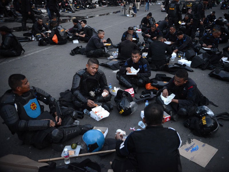 Anggota Korps Brigade Mobil (Brimob) berbuka puasa di sela-sela tugas mereka untuk mengamankan unjuk rasa di depan Gedung Bawaslu
