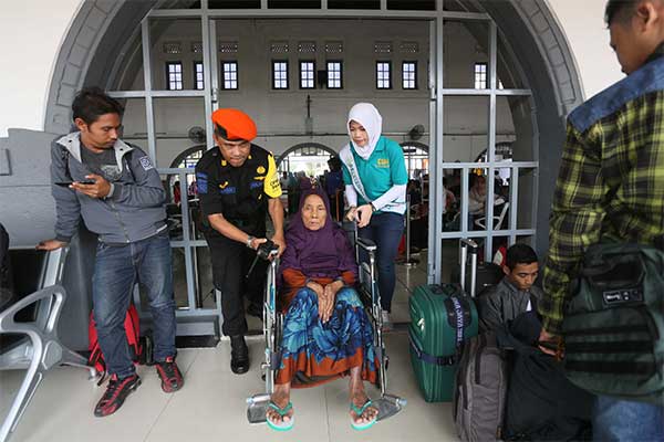 Petugas membantu penumpang lansia dengan kursi roda menuju peron tunggu kereta Kerta Jaya tujuan Surabaya Pasar Turi di stasiun Pasar Senen,