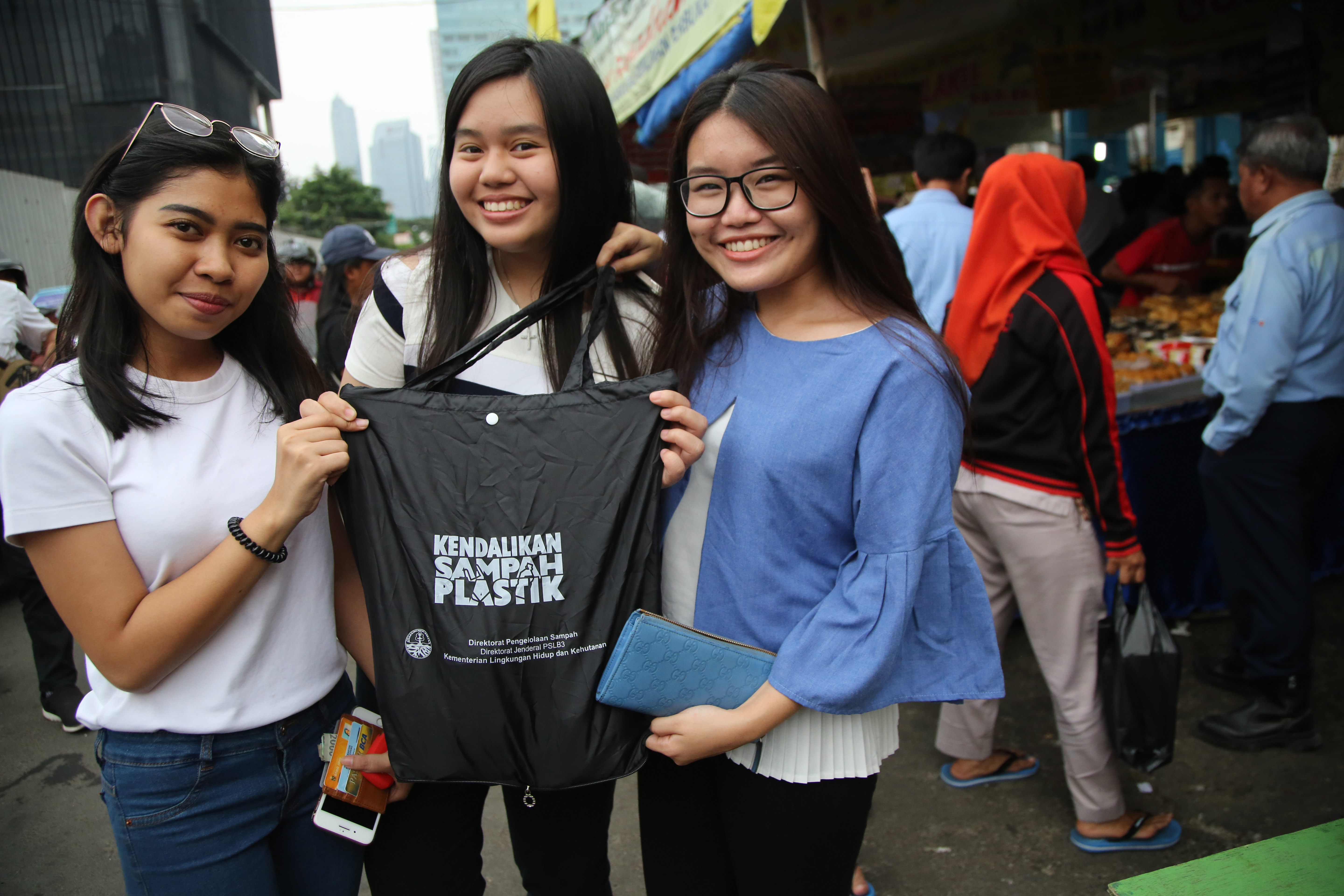 Petugas dari Kementerian Lingkungan Hidup dan Kehutanan menukar kantong plastik milik pembeli dengan tas ramah lingkungan