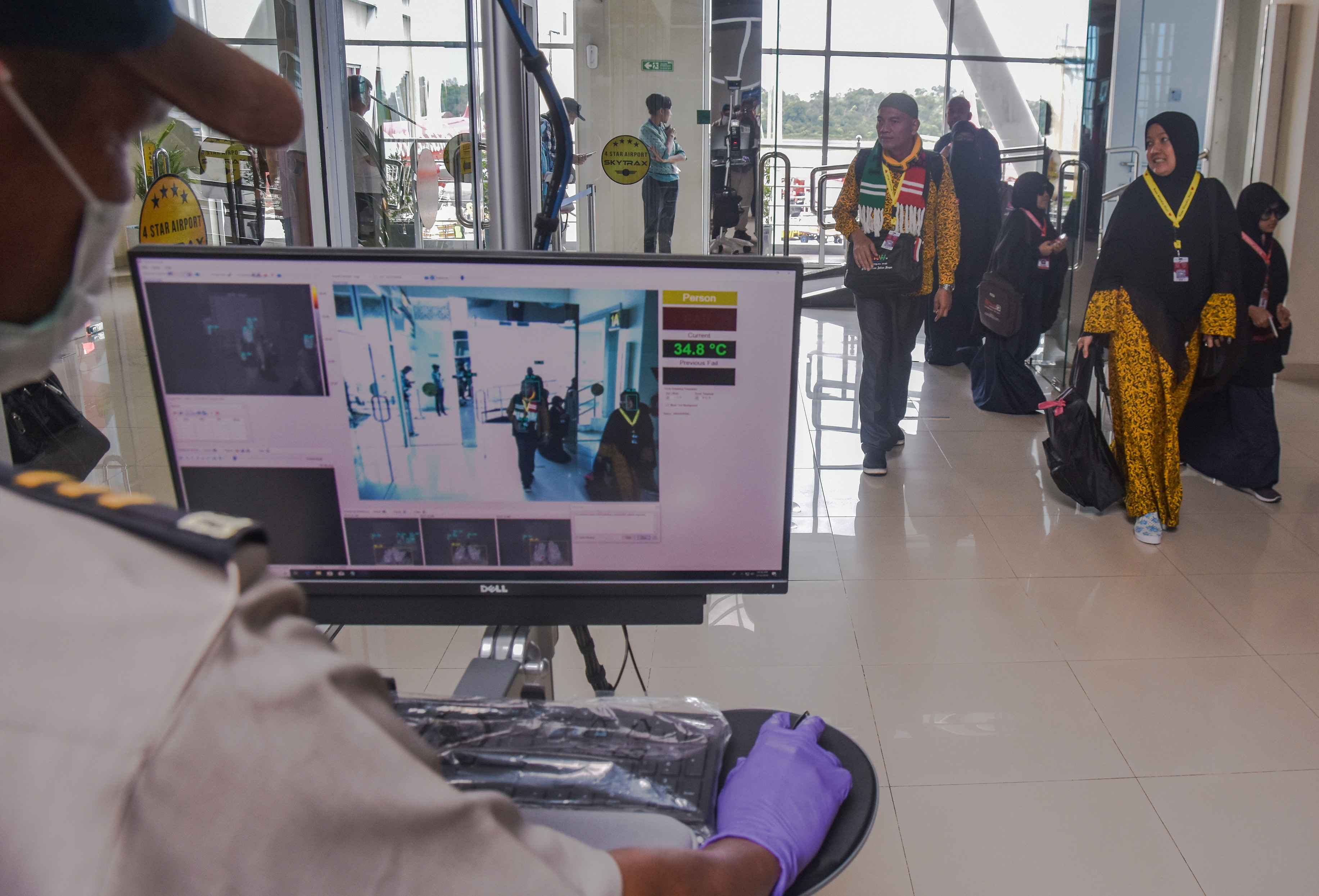 Sejumlah penumpang berjalan melewati alat pemindai panas tubuh di terminal kedatangan internasional Bandara Sultan Syarif Kasim II