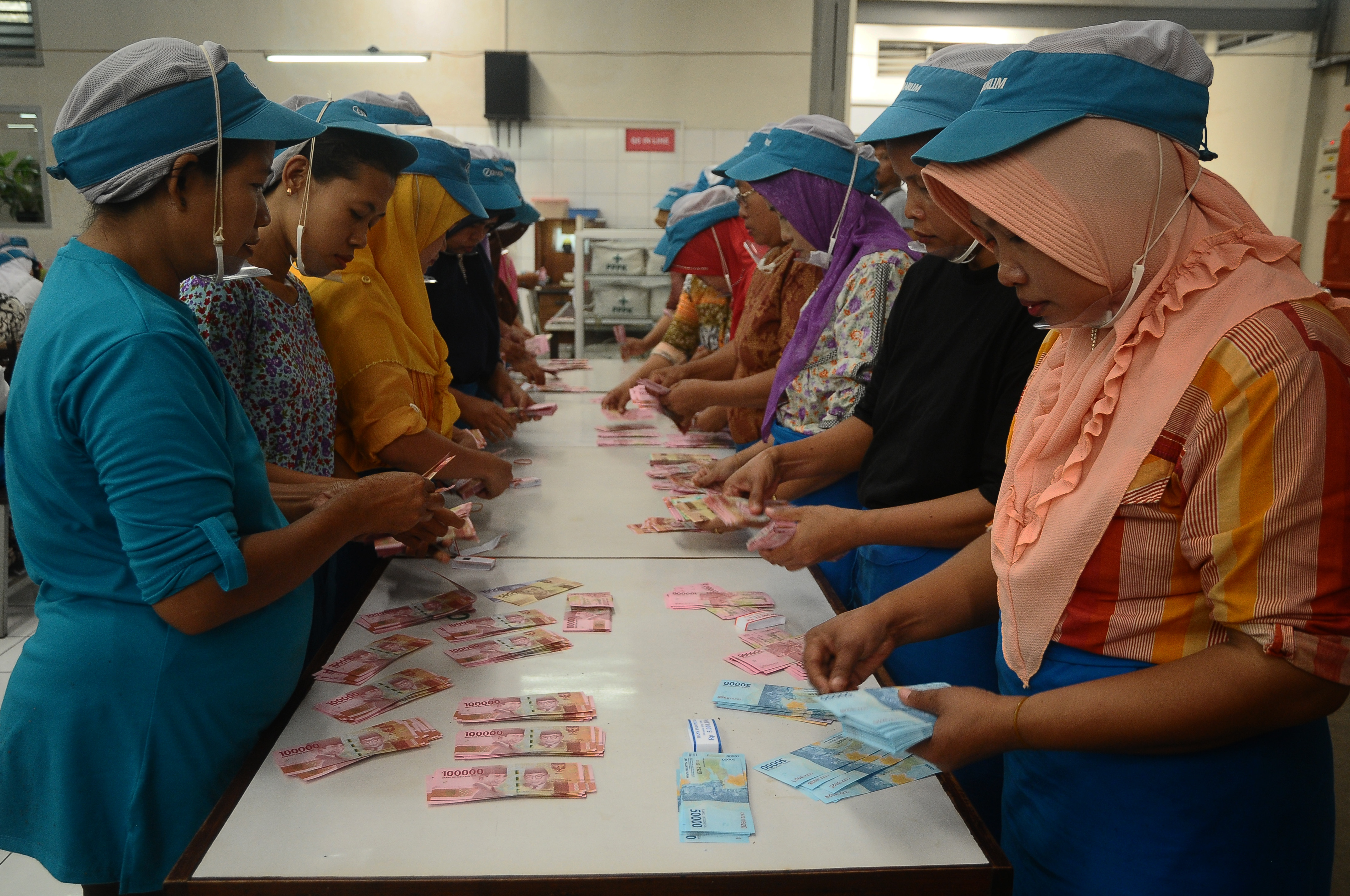 Sejumlah pekerja menghitung uang saat pembagian uang Tunjangan Hari Raya (THR) Lebaran di pabrik rokok, Kudus