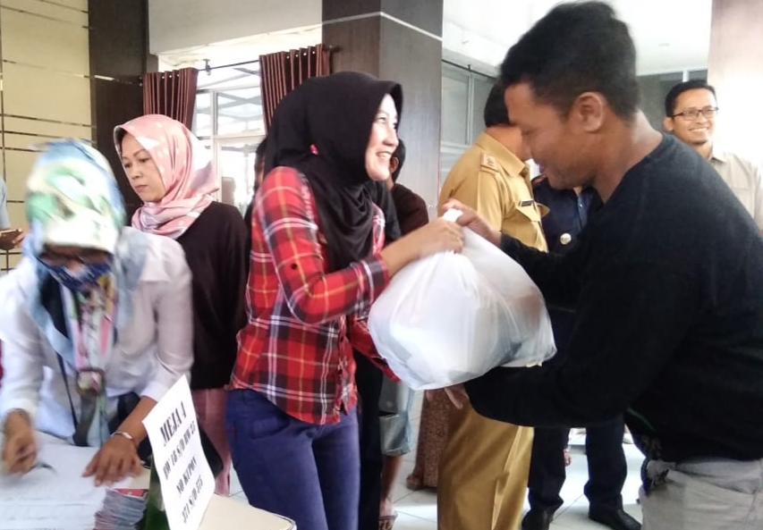  Seorang ibu rumah tangga menerima paket sembako saat operasi pasar murah (OPM) di Kantor Kecamatan Cimahi Utara, Selasa (21/5).