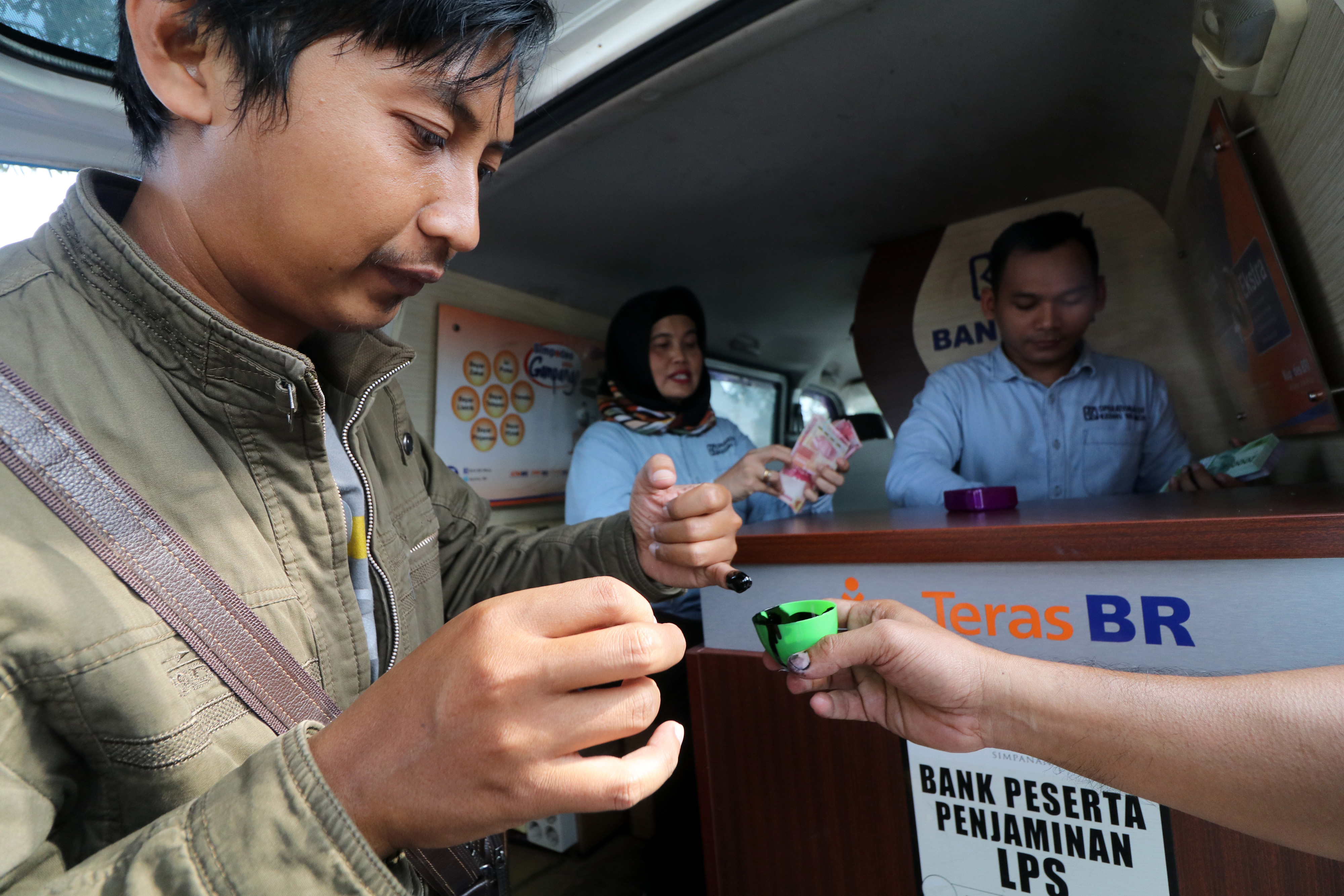 Warga mencelupkan jarinya ke dalam tinta usai menukarkan uang di mobil kas keliling di kawasan monumen Simpang Lima Gumul, Kediri, Jatim.