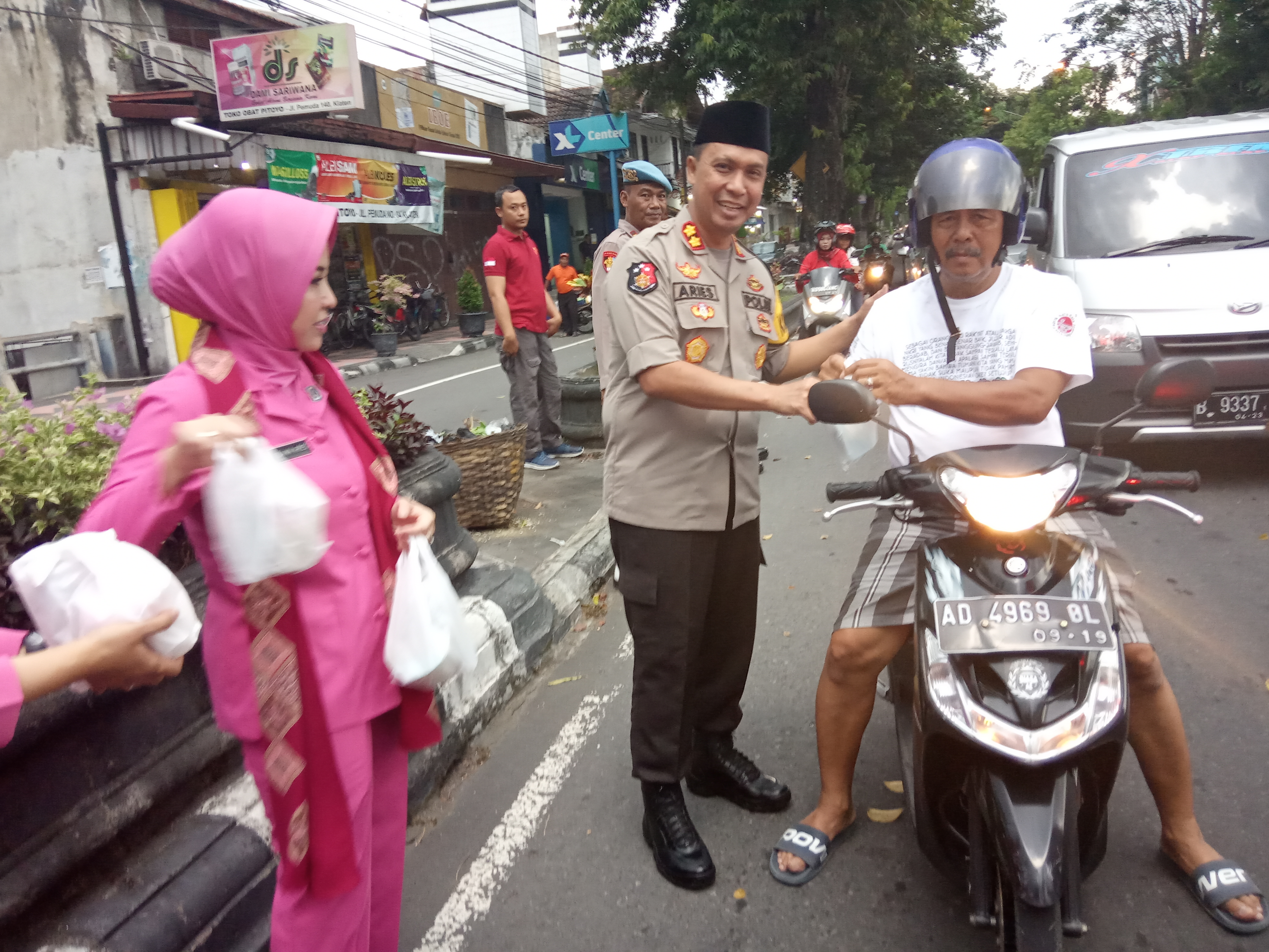 Kapolres AKB Aries Andhi didampingi Ketua Cabang Bhayangkari Klaten, Diana Aries, menyerahkan takjil kepada pengendara sepeda motor.