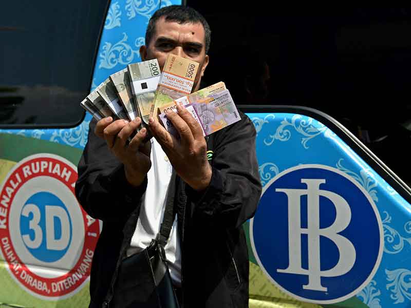 Warga memperlihatkan uang yang baru ditukarkan di loket mobil kas keliling milik Bank Indonesia