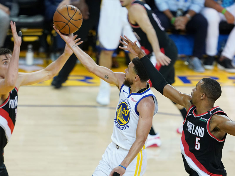 Pemain Golden State Warriors Stephen Curry melakukan lay up diantara pemain Portland Trailblazers