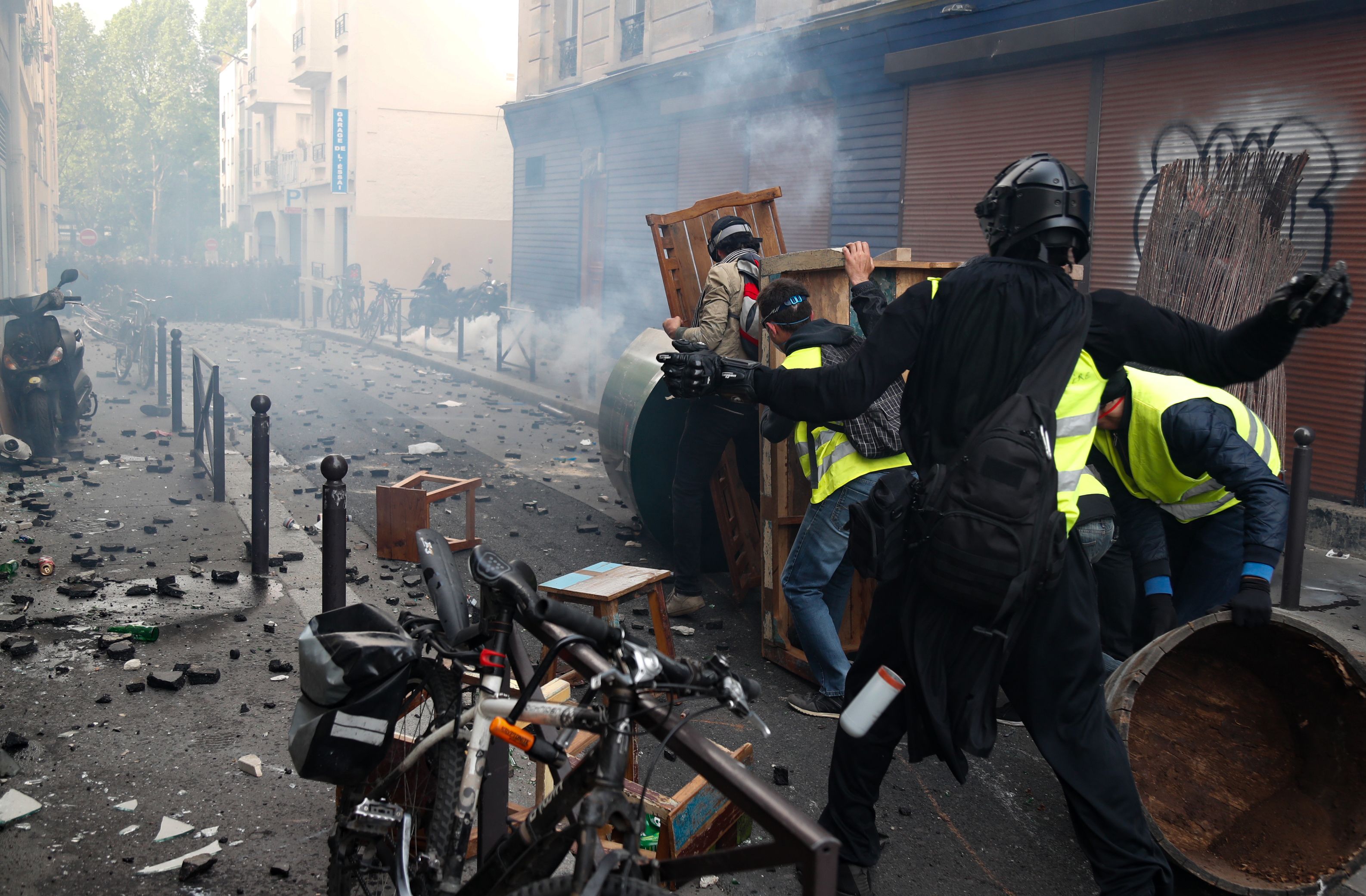 Seorang demonstran melemparkan batu ke arah polisi antihuru-hara dalam bentrokan di Hari Buruh di Paris, Prancis.