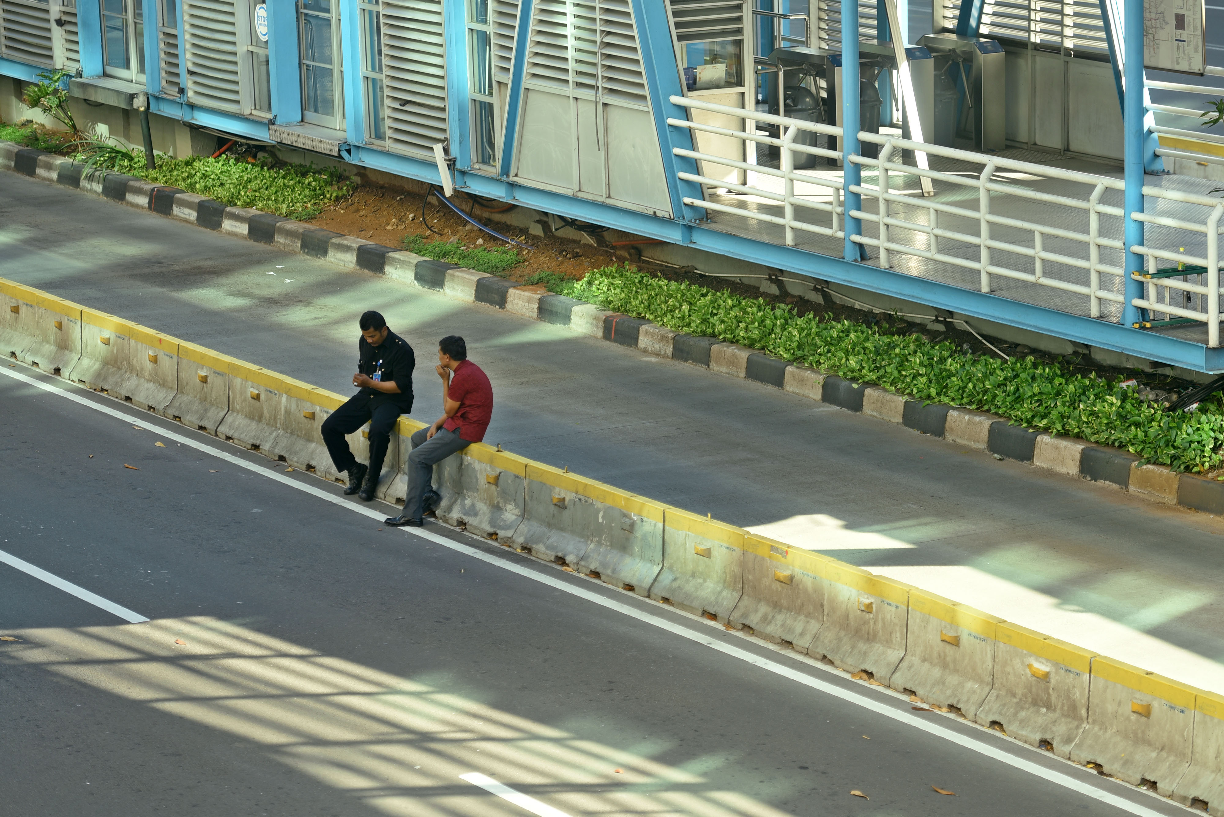 Dua warga duduk di atas beton pemisah jalur TransJakarta di Jalan MH Thamrin, Jakarta Pusat, Jumat (24/5/2019)