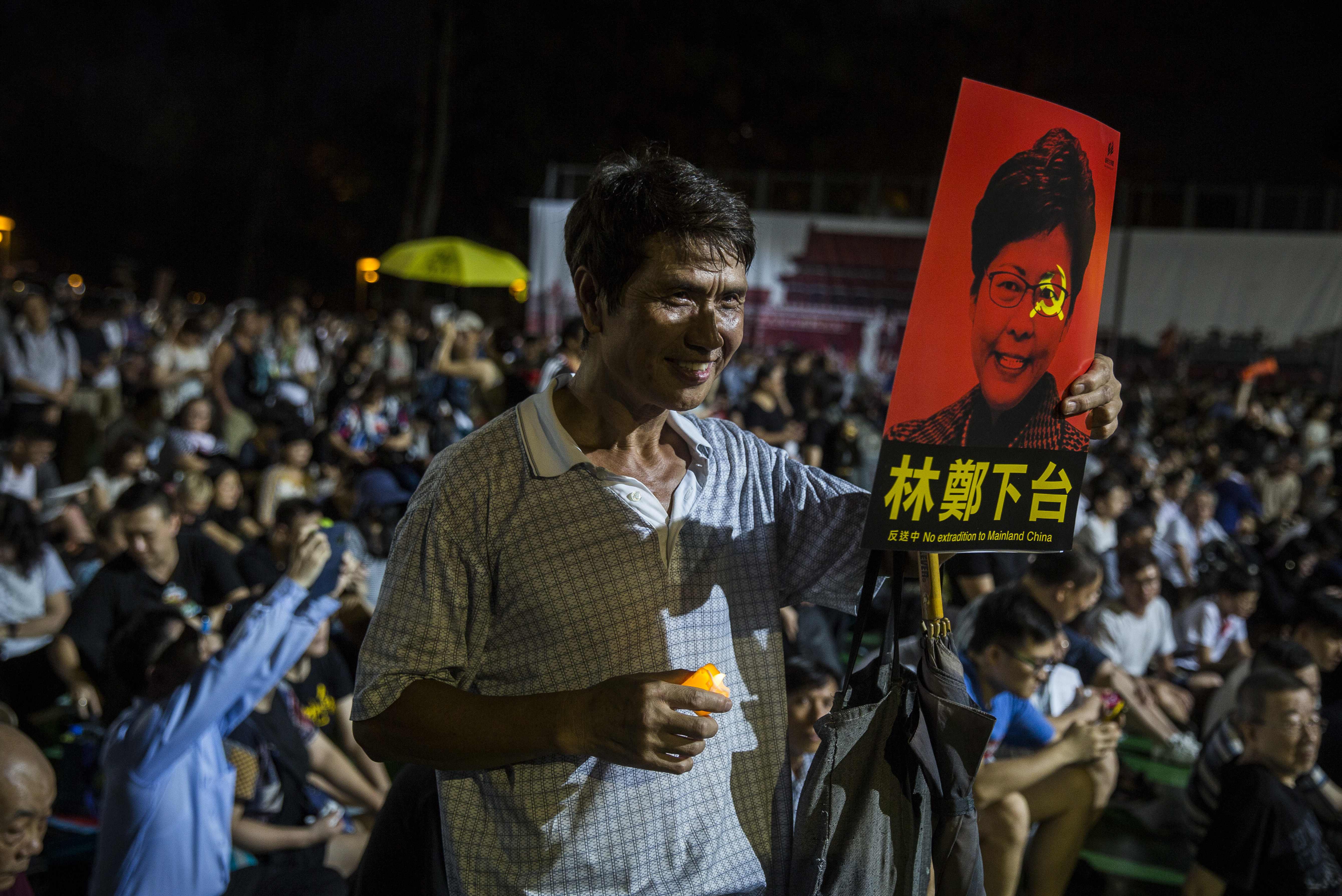 Seorang pria memegang poster pemimpin pemerintah Hong Kong, Carrie Lam saat demonstrasi di Hong Kong.