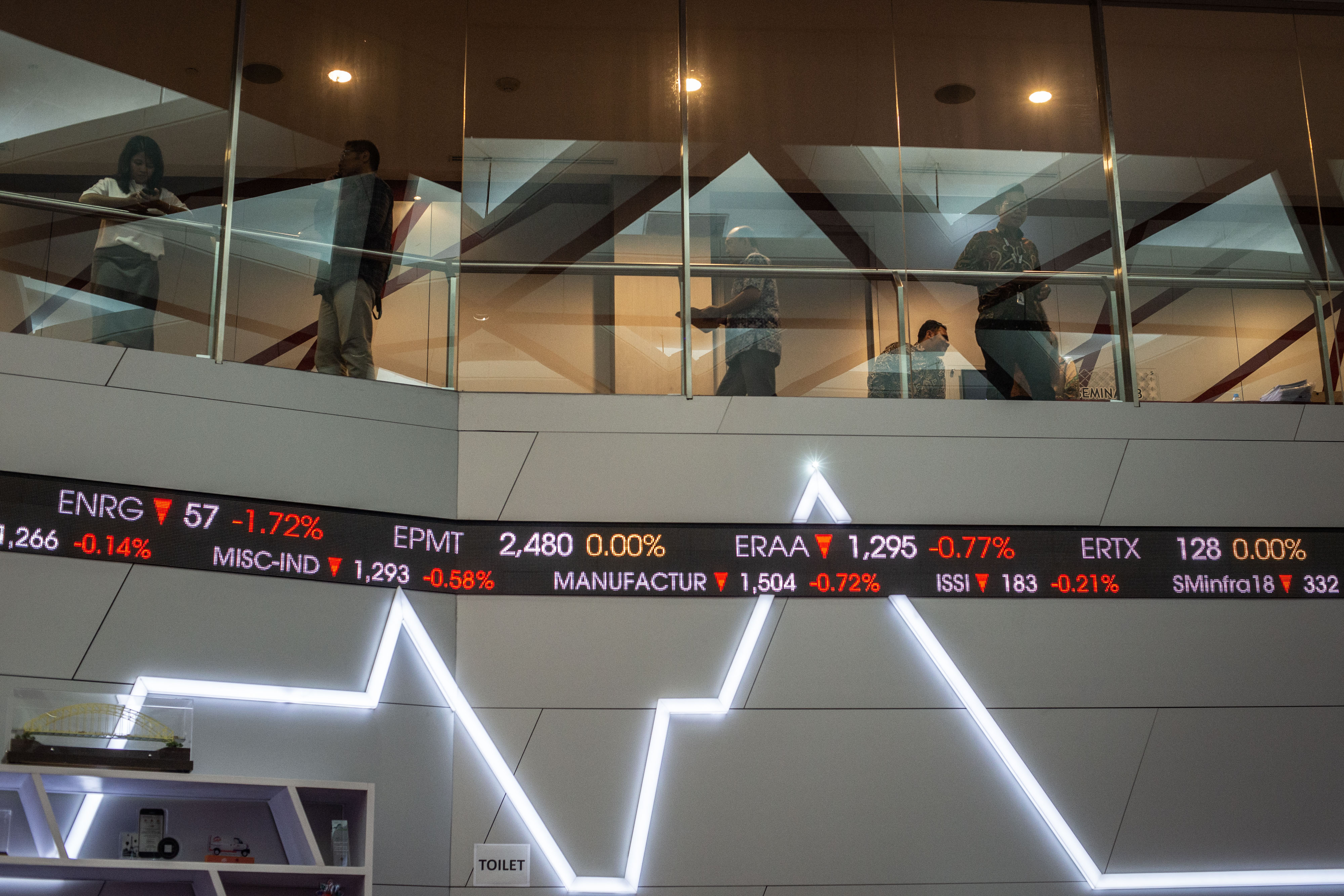 Karyawan beraktivitas di dekat grafik pergerakan saham di gedung Bursa Efek Indonesia, Jakarta.