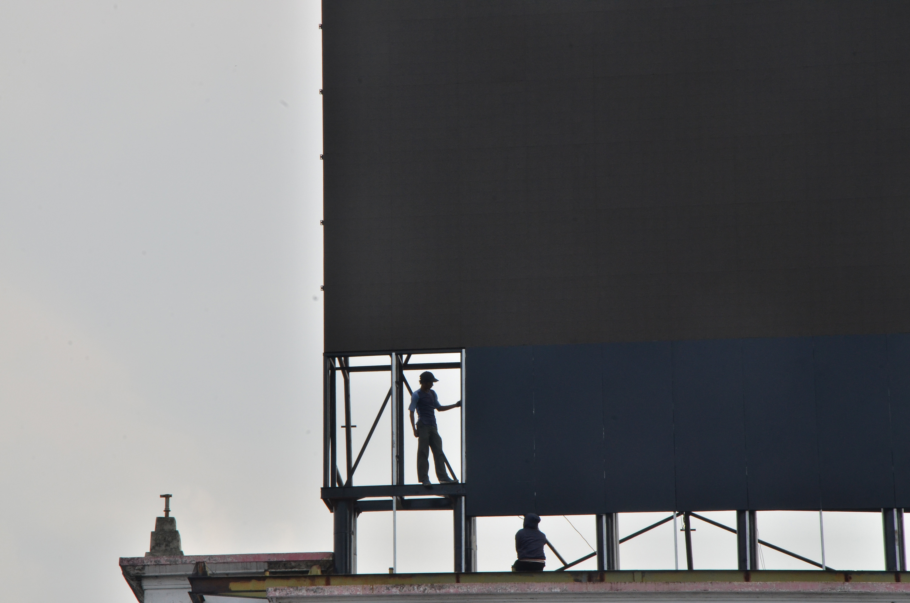 Pekerja memperbaiki papan reklame sebelum diganti dengan materi iklan yang baru di kawasan Harmoni, Jakarta.