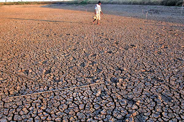 Petani berjalan di areal embung yang mengering di Balongan, Indramayu, Jawa Barat, kemarin.