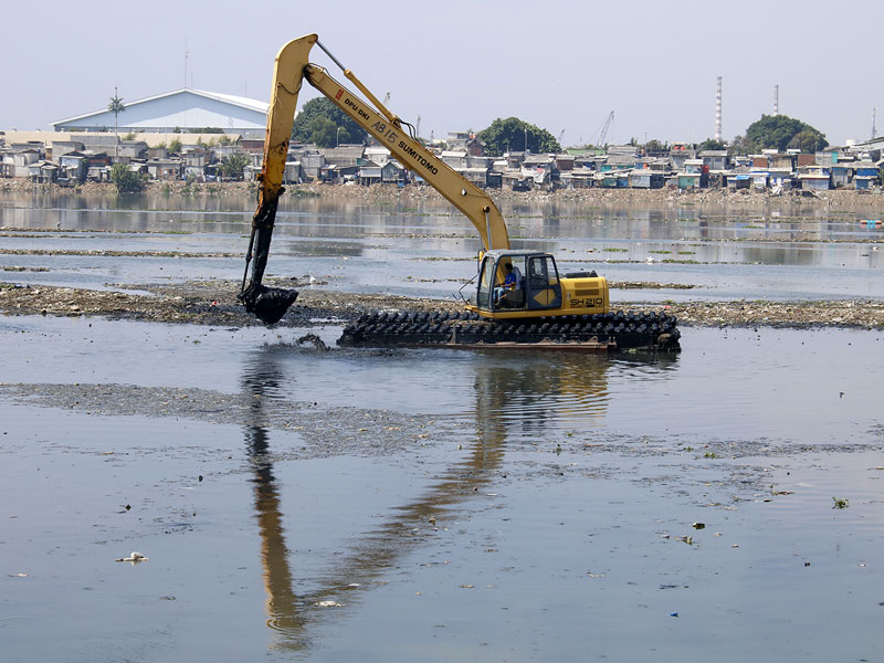 Petugas Dinas Sumber Daya Air menggunakan alat berat mengeruk Waduk Pluit yang kondisinya mengalami pendangkalan.