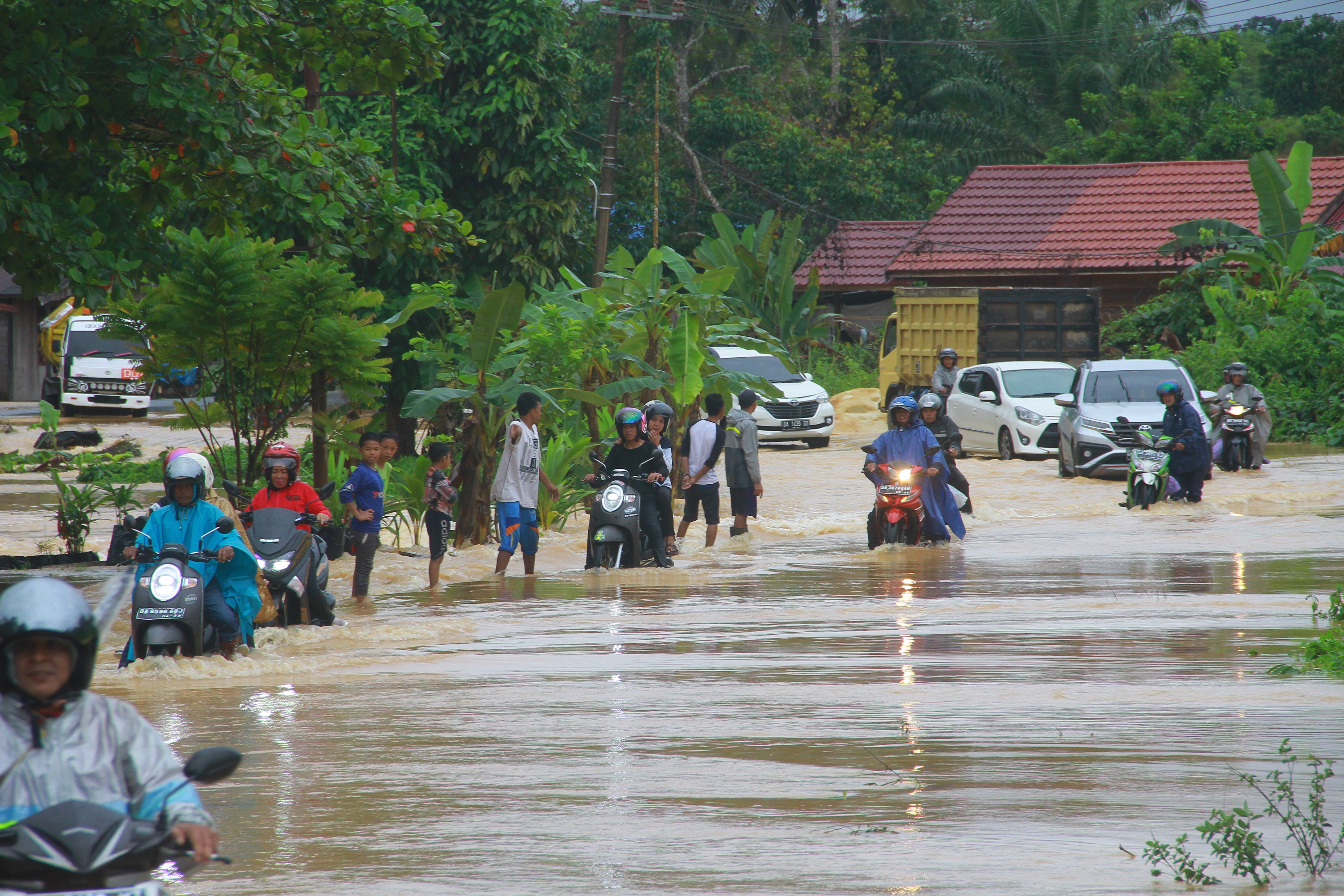Sejumlah pengendara melintasi Jalan Poros Pulau Laut yang terendam banjir di Desa Sungup Kanan, Kabupaten Kotabaru,