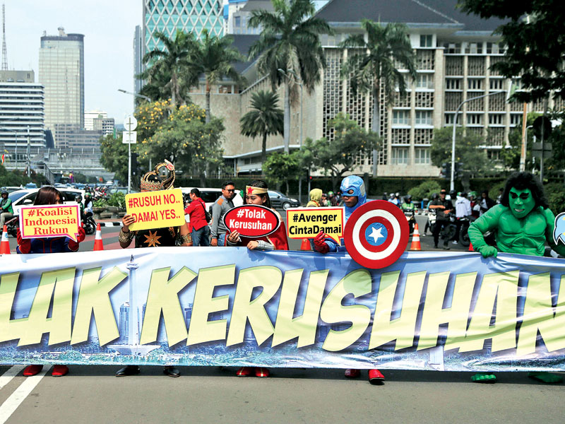 Sejumlah peserta aksi berkostum superhero melakukan aksi damai di Jalan Merdeka Barat, kemarin.