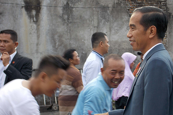 Presiden RI, Joko Widodo menyapa warga kurang yang sedang menunggu giliran pengambilan paket sembako di Gedung Graha Saba Buana, Surakarta