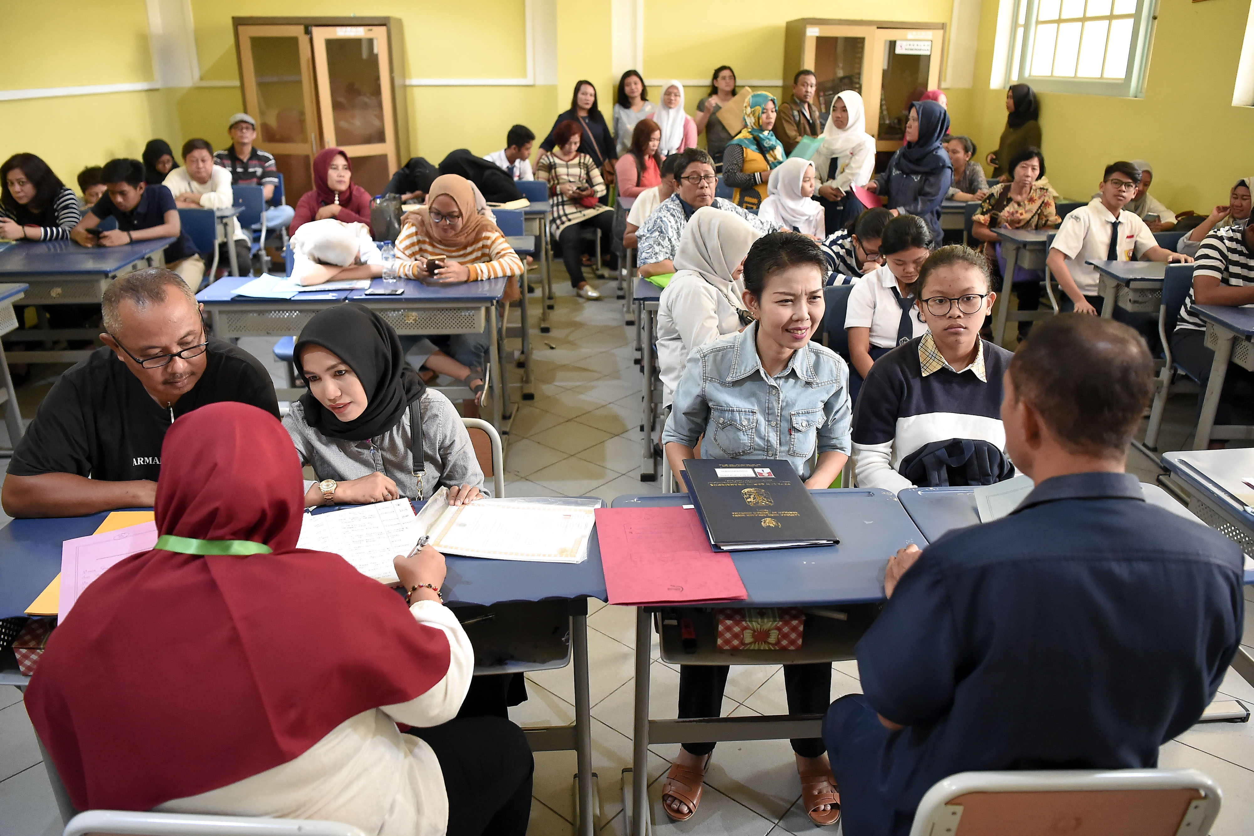  Sejumlah siswa dan orang tua murid mendaftar seleksi Penerimaan Peserta Didik Baru (PPDB) menggunakan komputer di SMAN 1 Jakarta