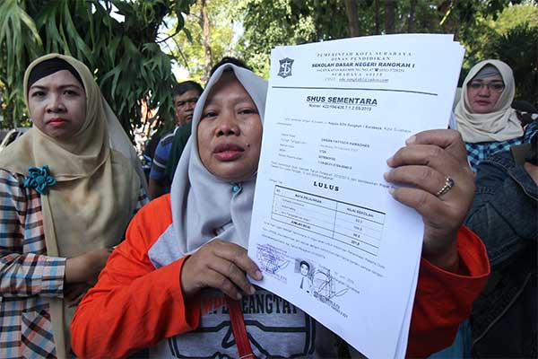 Warga menunjukkan Surat Hasil Ujian Sementara (SHUS) saat berunjukrasa di Balai Kota Surabaya, Jawa Timur, Rabu (19/6/2019). 