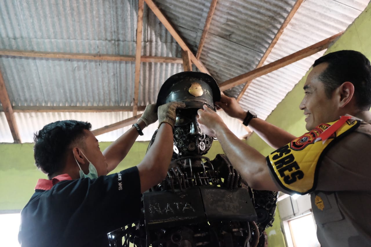 Kapolres Karawang AKB Nuredy Irwansyah Putra (kanan) memasangkan topi polisi kepada robot polisi buatan siswa SMK Karya Utama. 