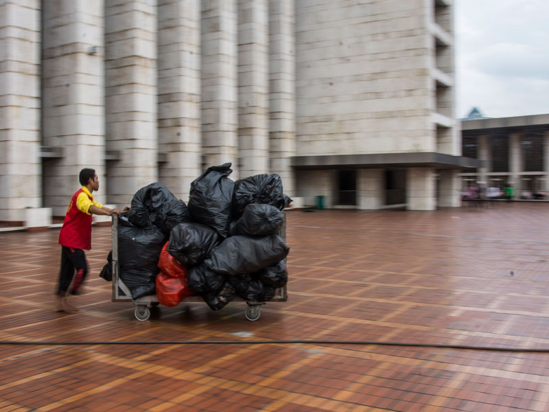 Petugas kebersihan Masjid Istiqlal mendorong gerobak sampah di bagian dalam Masjid Istiqlal, Jakarta.