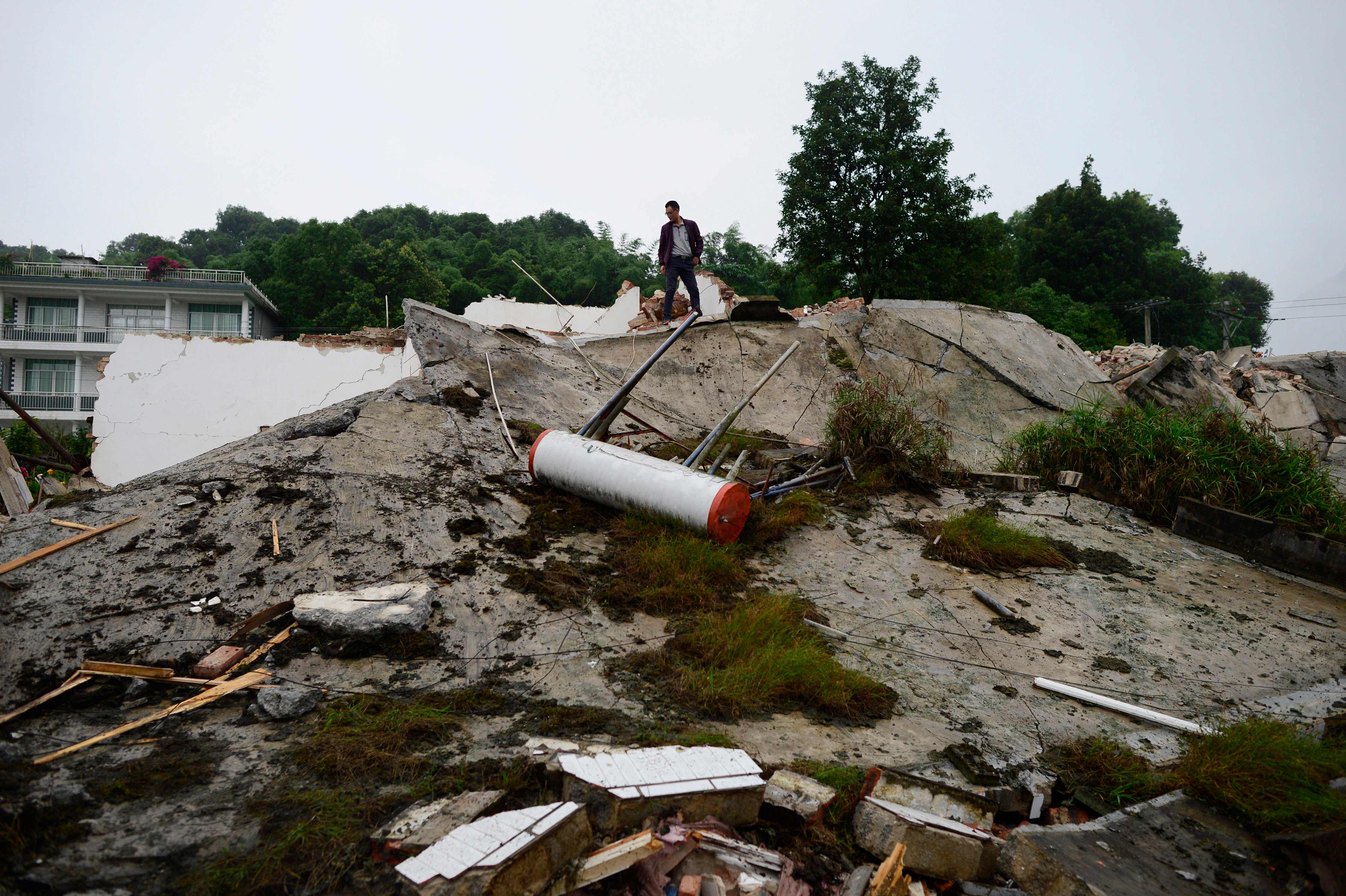 Seorang lelaki berdiri di atas bangunan yang runtuh di Yibin, di provinsi Sichuan di Cina barat daya pada 18 Juni 201