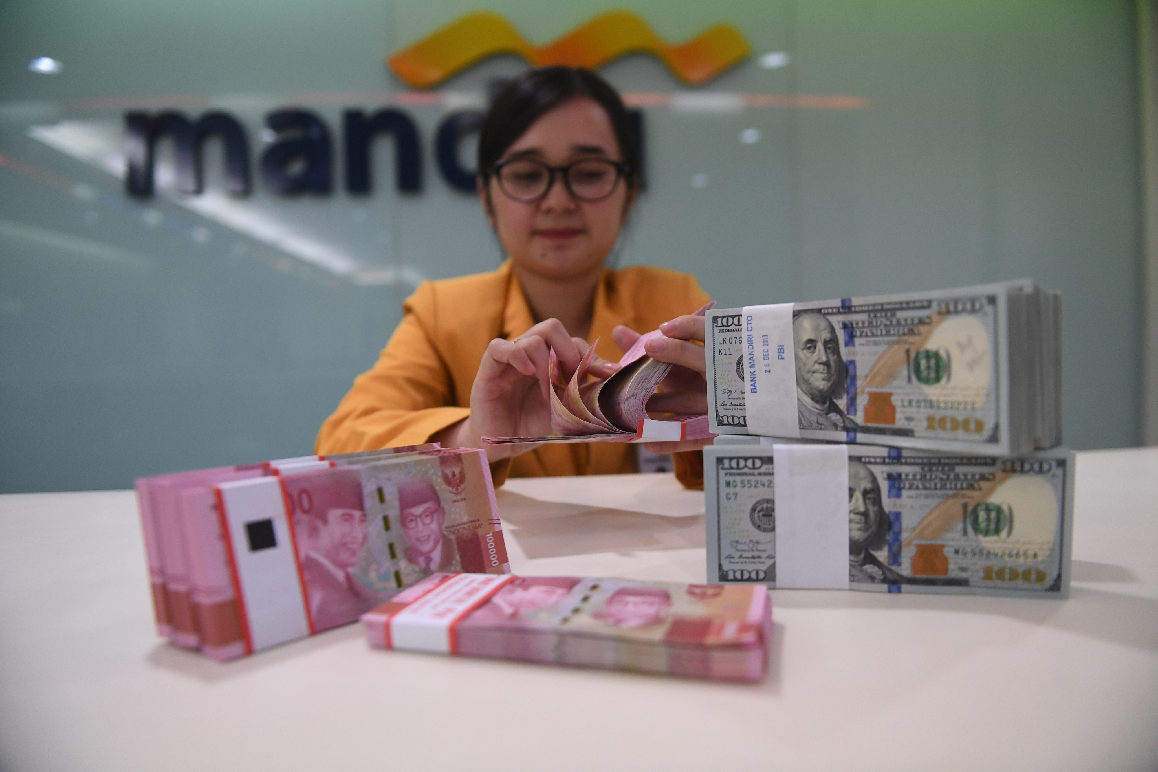 Seorang Teller menghitung uang Rupiah dan Dolar Amerika Serikat di Bank Mandiri, Jakarta