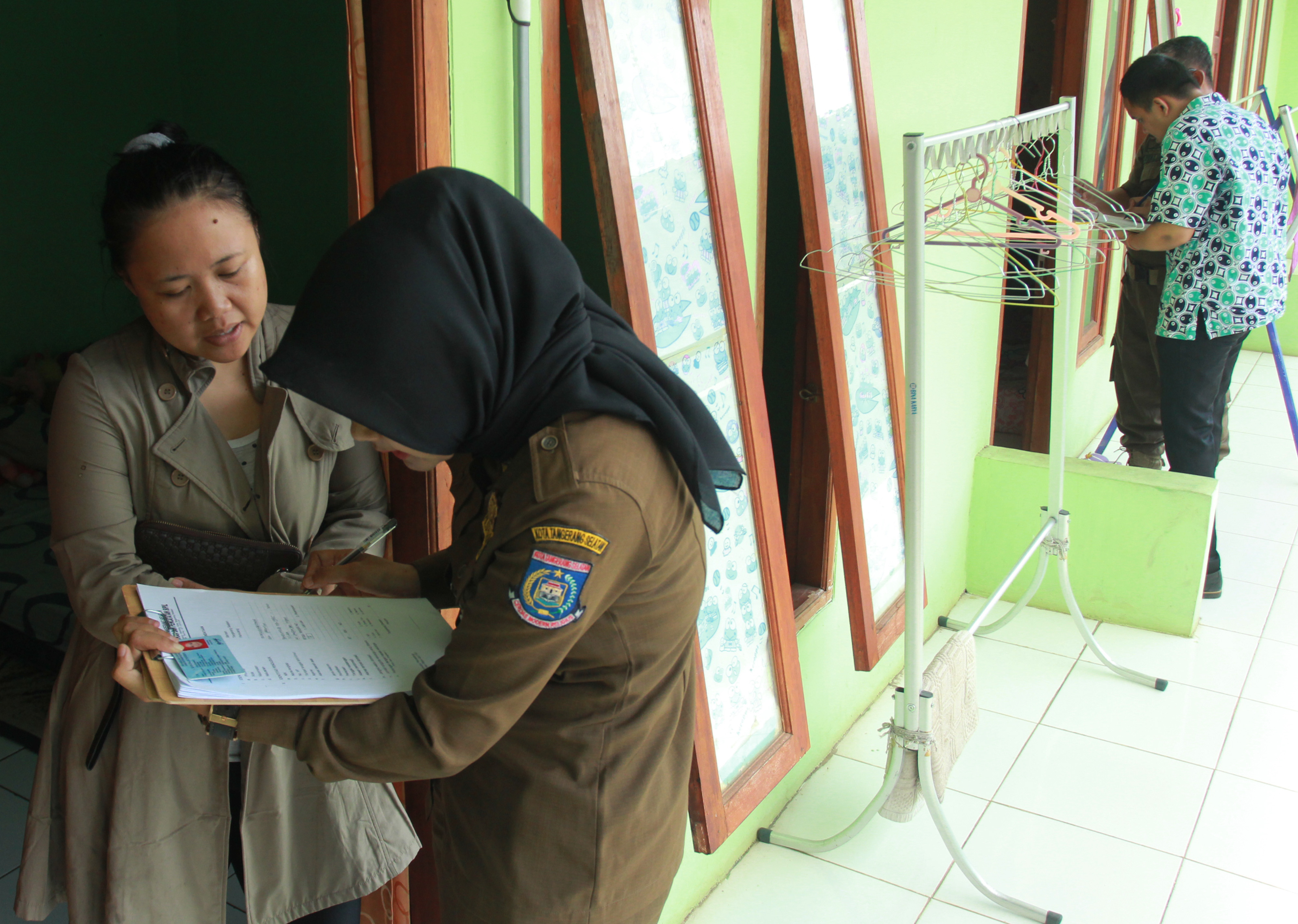Petugas Satpol PP Kota Tangerang Selatan memeriksa KTP warga saat Pendataan Bina Kependudukan pasca-Lebaran di rumah kontrakan di Ciputat.
