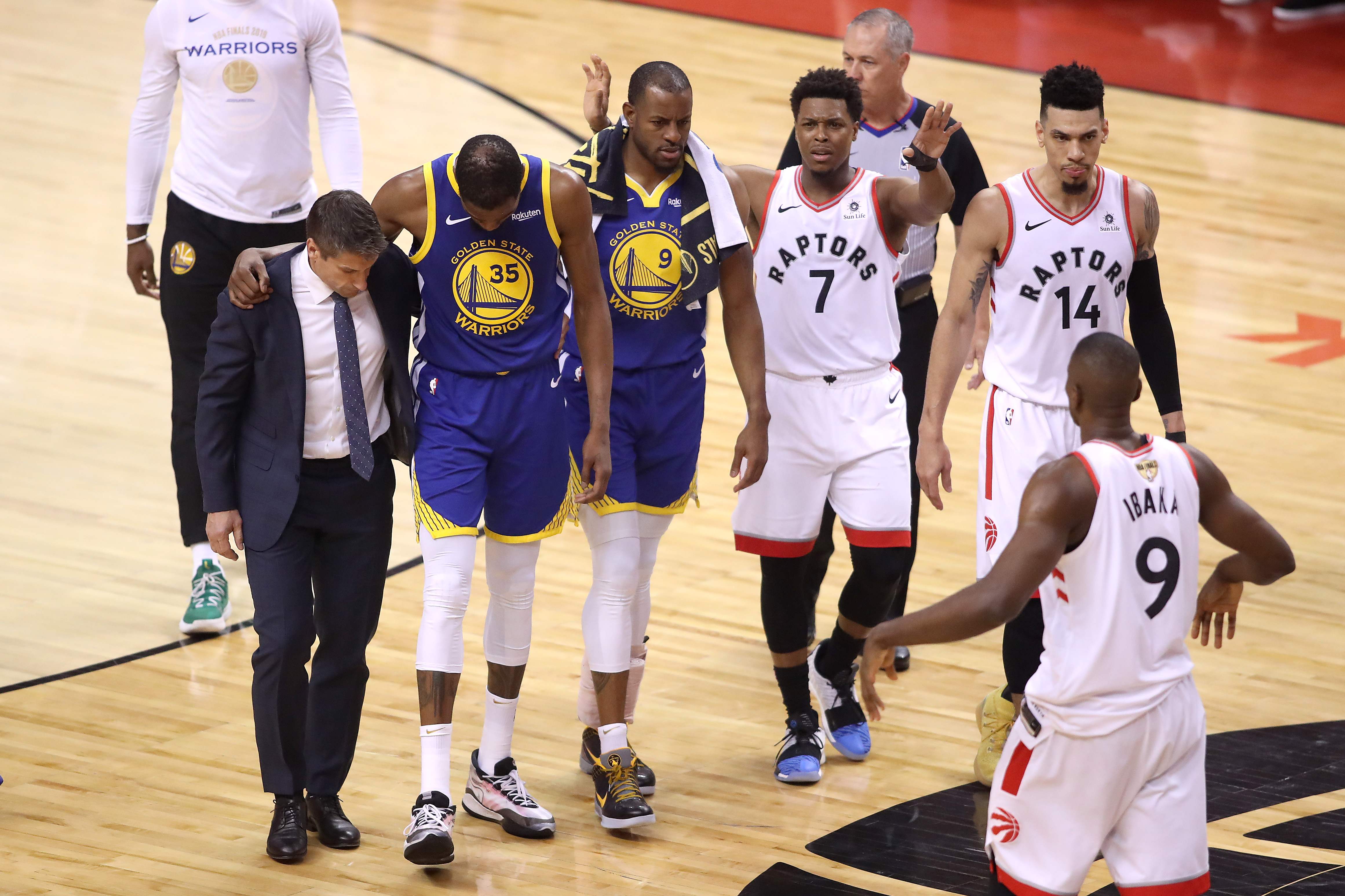 Kevin Durant (kedua dari kiri) meninggalkan lapangan dibantu staf pelatih Warriors di Gim 5 final NBA.