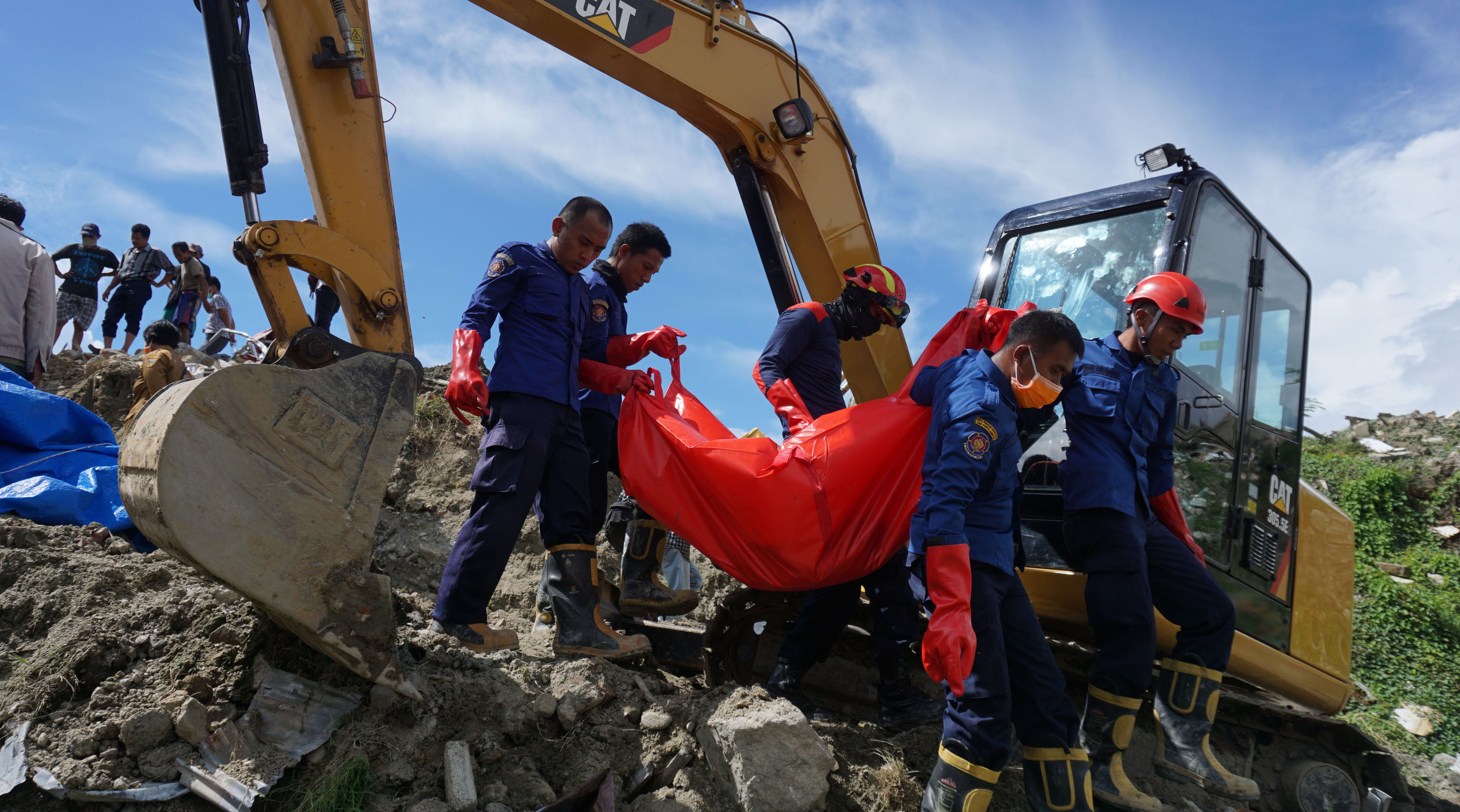  Petugas mengangkat kantong berisi jenazah korban bencana gempa dan likuefaksi di Kelurahan Petobo, Palu