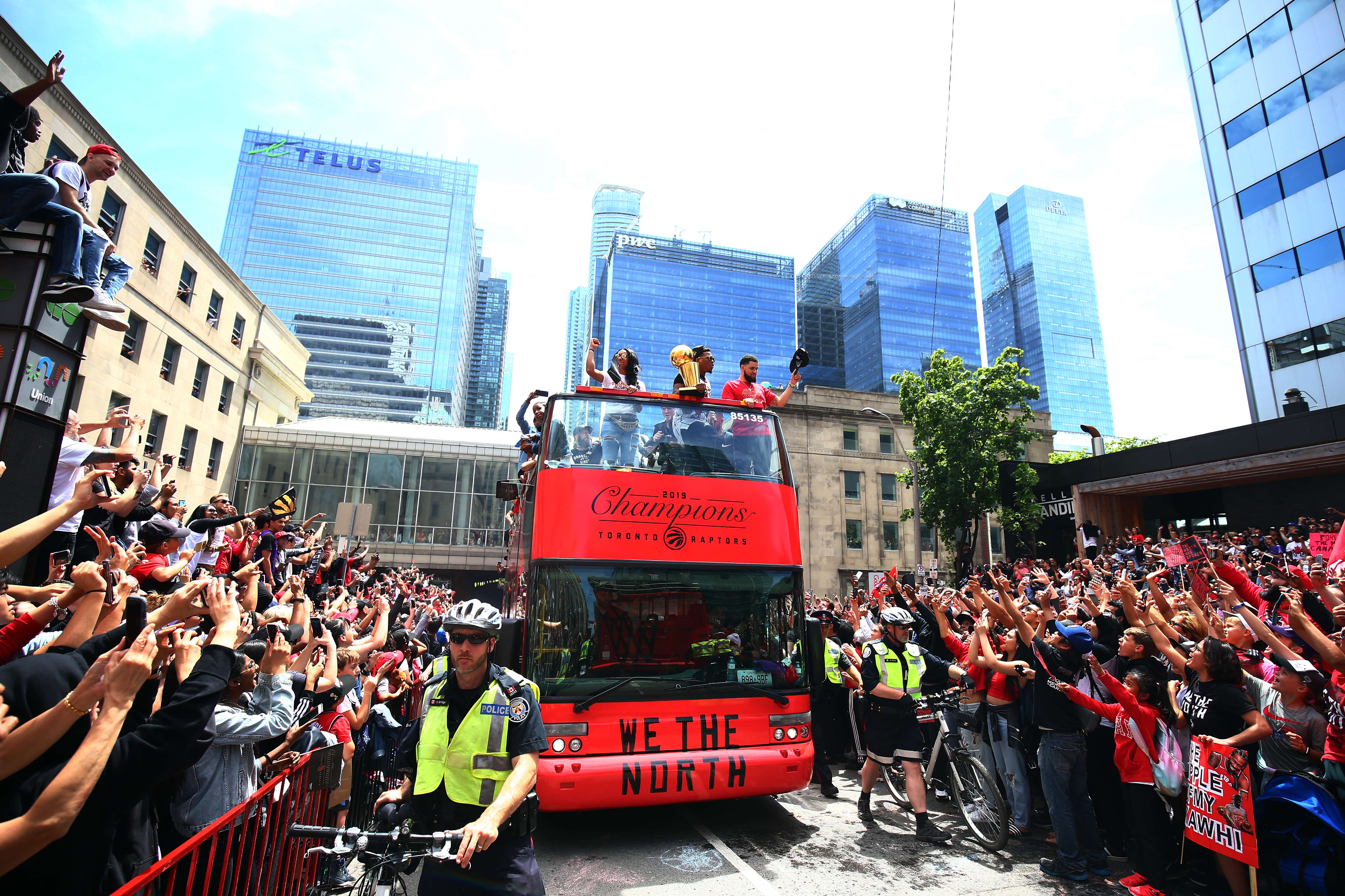Bus yang mengangkut para pemain Raptors melewati ribuan pendukung mereka dalam parade merayakan keberhasilan mereka menjadi juara NBA.