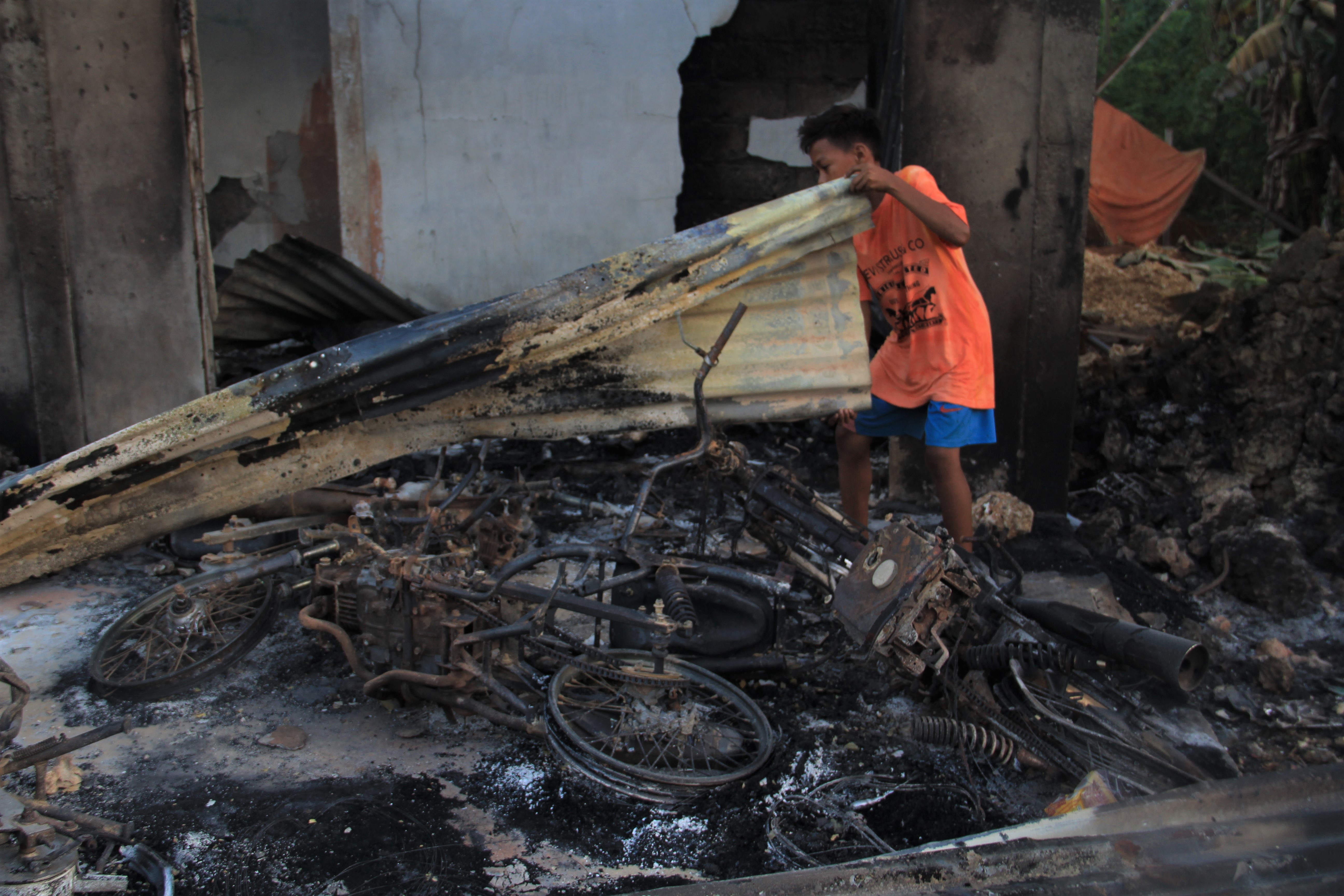 Warga berada di bangkai dua unit sepeda motor yang terbakar di dalam rumah di Desa Gunung Jaya, Buton, Sulawesi Tenggara, Kamis (6/6).
