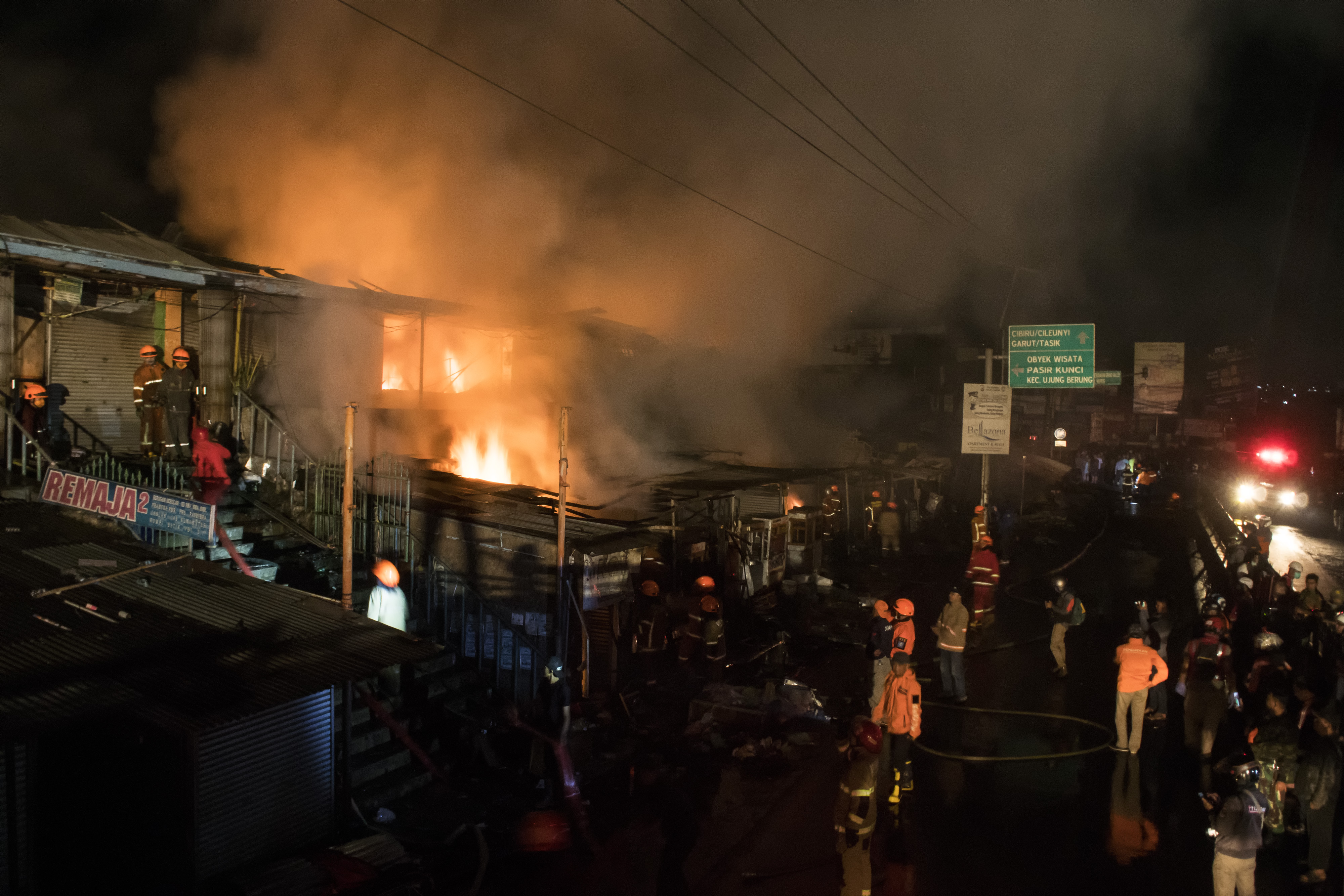 Petugas berusaha memadamkan api saat terjadi kebakaran sejumlah kios Pasar Ujungberung, Bandung, Jawa Barat, Minggu (9/6/2019) malam