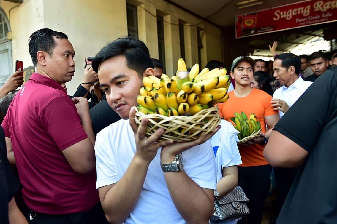 Presiden Jokowi dan kedua putranya, Gibran Rakabuming Raka dan Kaesang Pangarep, membawa pisang hasil belanjaan.