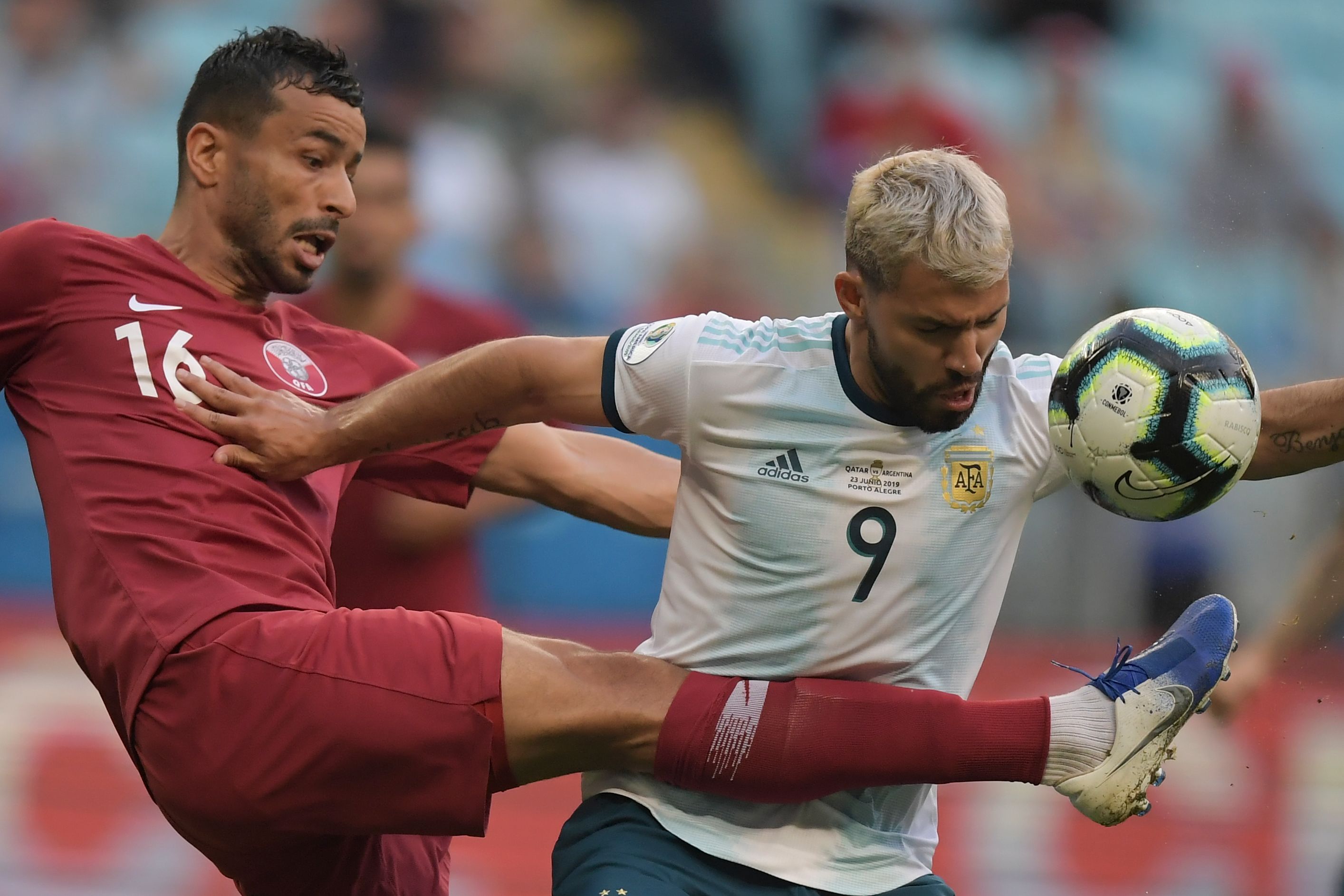 Pesepakbola Qatar, Boualem Khoukhi (kiri) berebut bola dengan pemain Argentina, Sergio Aguero dalam laga Copa America, Minggu (23/6).