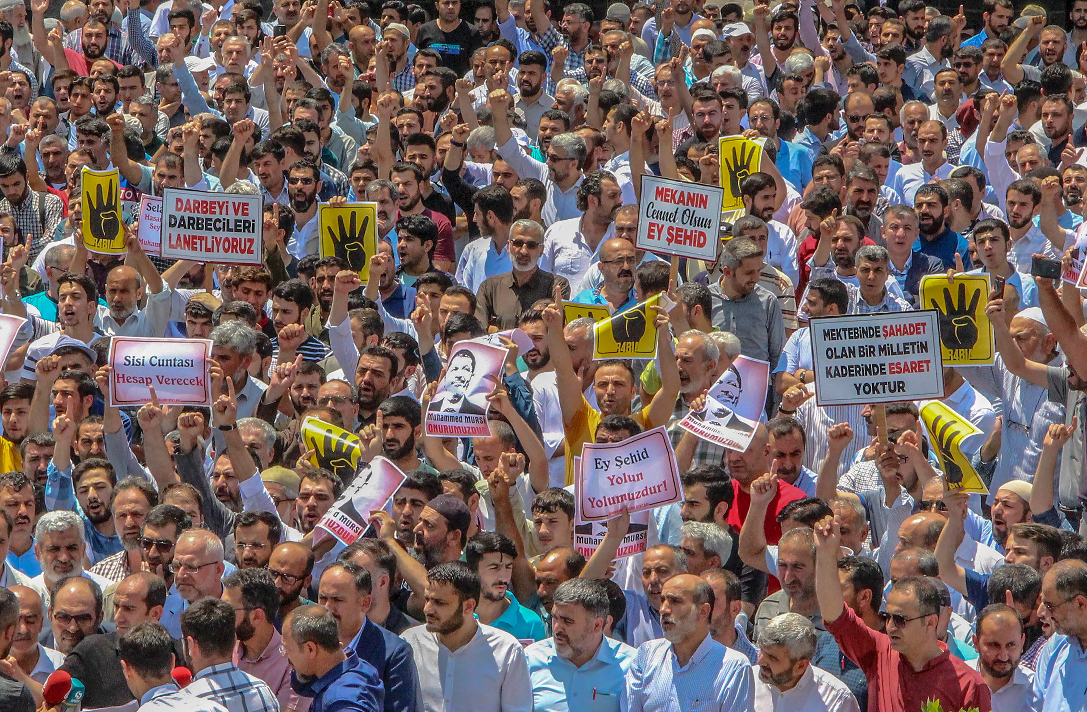 Ratusan IM memegang foto-foto mantan presiden Mesir Mohamed Mursi dalam sebuah doa pemakaman simbolis sehari setelah dia meninggal \